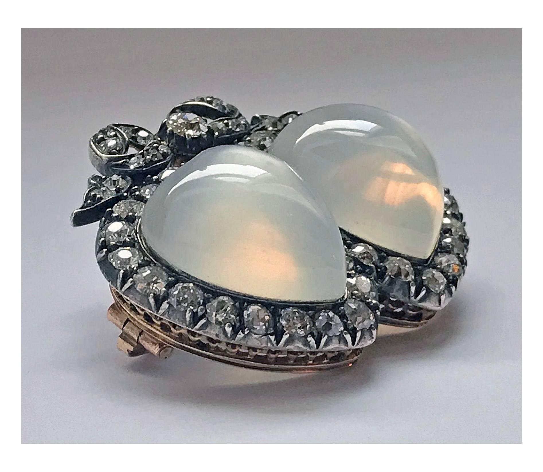 Late 19th century double heart moonstone and diamond Brooch. English, C.1890. The Brooch set with two large heart moonstone,  each gauging approximately  16 x 14 mm, the surround mount and festoon above set with fifty four old cut diamonds,