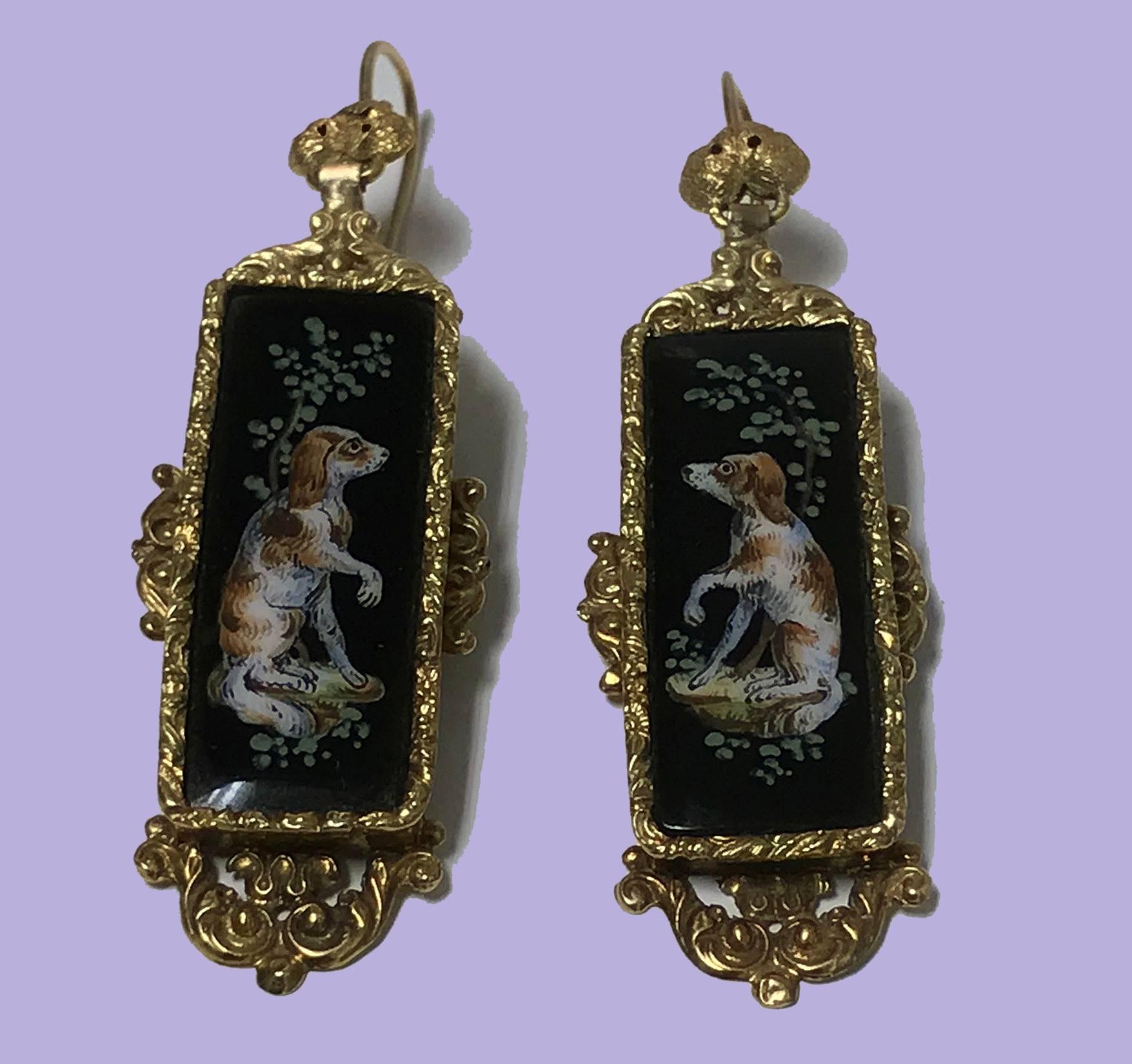 Pair of Antique 18K Enamel `Spaniel’ Earrings, Continental, C.1875. Each of rectangular drop form depicting an enameled seated spaniel with raised paw on black background in sylvan landscape, 18K (tested) gold foliage surround border, hook clip