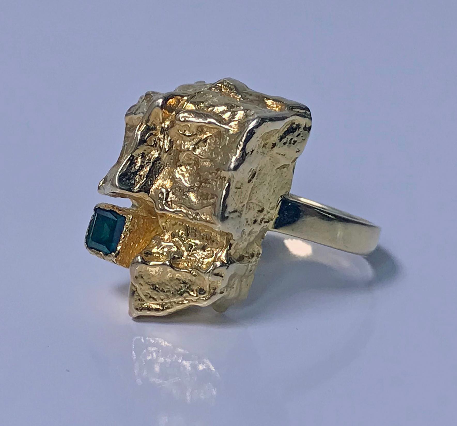 1970’s Scandinavian Gold and Emerald abstract Ring. The Ring of large textured abstract gold nugget form set in the corner with a slightly bluish Green square cut emerald, approximately 0.30 ct, approximately VS clarity (type 111), plain polished