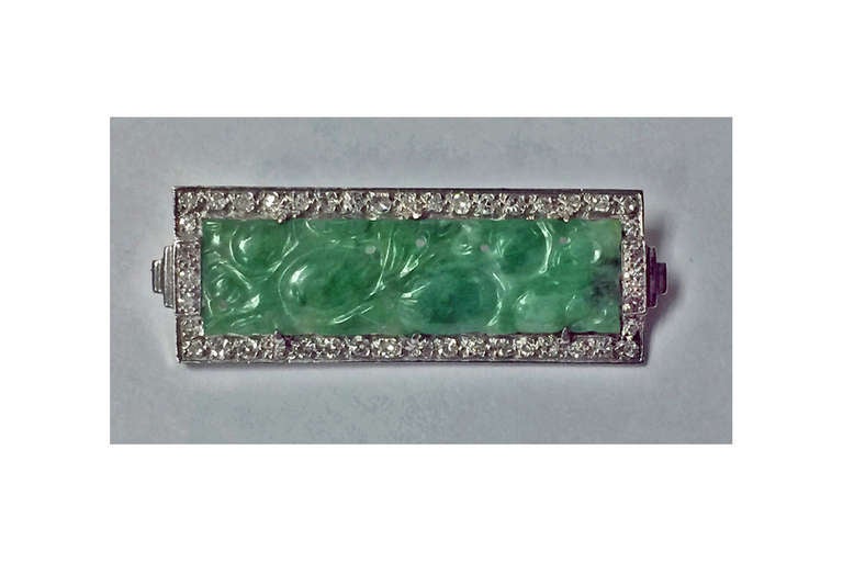 18K carved Jade and Diamond Brooch., C.1940.The centre with carved rectangular jade panel, , the surround mount set with 44 single cut diamonds, total diamond weight approximately 0.70 ct, average SI clarity, average I colour. Stamped 18K on