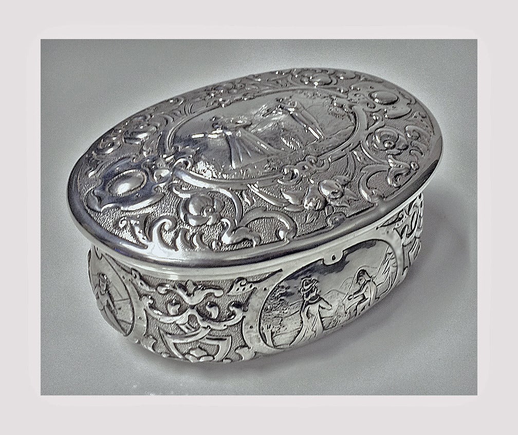 Large 19th century Hanau silver box, C.1900. Each side of oval shape box with romantic figural scene. The hinged cover with figures playing musical instruments. Measures 5 x 3 3/4