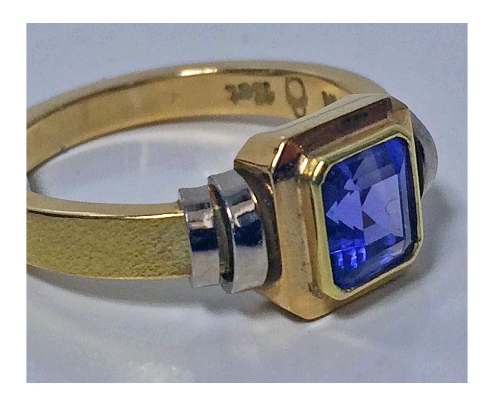 Tanzanite 18ct yellow & white gold Ring, Peter Cullman. The ring bezel centre set with square tanzanite, 1.10 ct, ribbed white gold shoulders matte satin shank. Stamped 18ct Cullman. Item weight: 4.81 gm. Ring size: 6.5.Peter Cullman worked at Egon