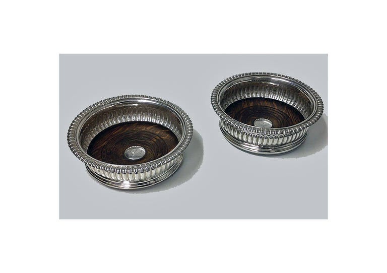 Pair of Georgian Silver Wine Coasters, Sheffield 1825, John Watson. The coasters on molded circular base, lobate surround, gadroon rim. The turned wood centres with silver bosses engraved with the crest of a stag and motto surround…`juste sans