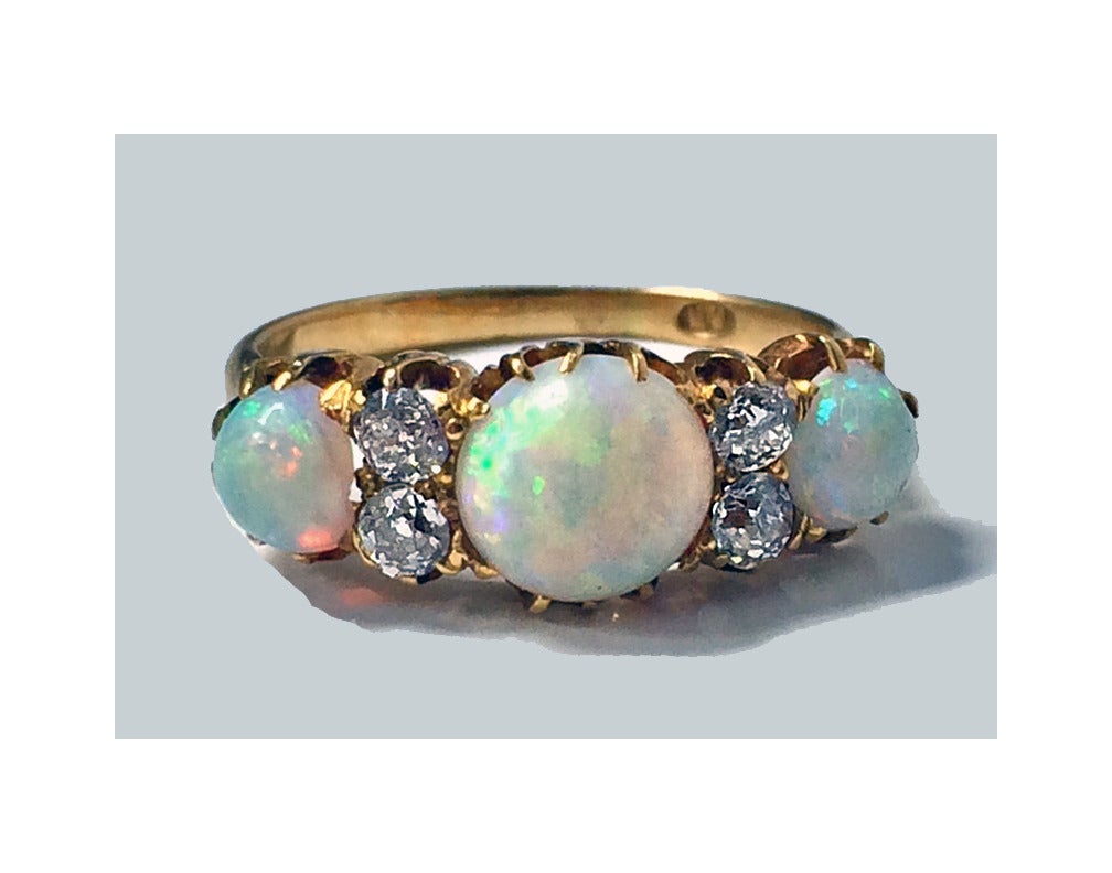 Antique 18K rose gold Opal and Diamond carved half hoop ring, C.1900. The ring claw set with three graduated oval cabochon opals interspaced with four old mine cut diamonds, total diamond weight approximately 0.45 ct, average SI clarity, average J