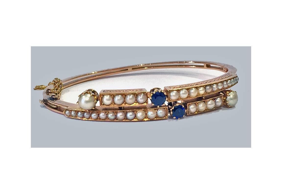 Antique 15K rose Gold Sapphire and Pearl Bangle, English C.1890. The Bangle of offset twist design set with a total of 18 small graduated half pearls and two round facetted blue sapphire, all with engraved foliate mount. The hinged bangle with plain