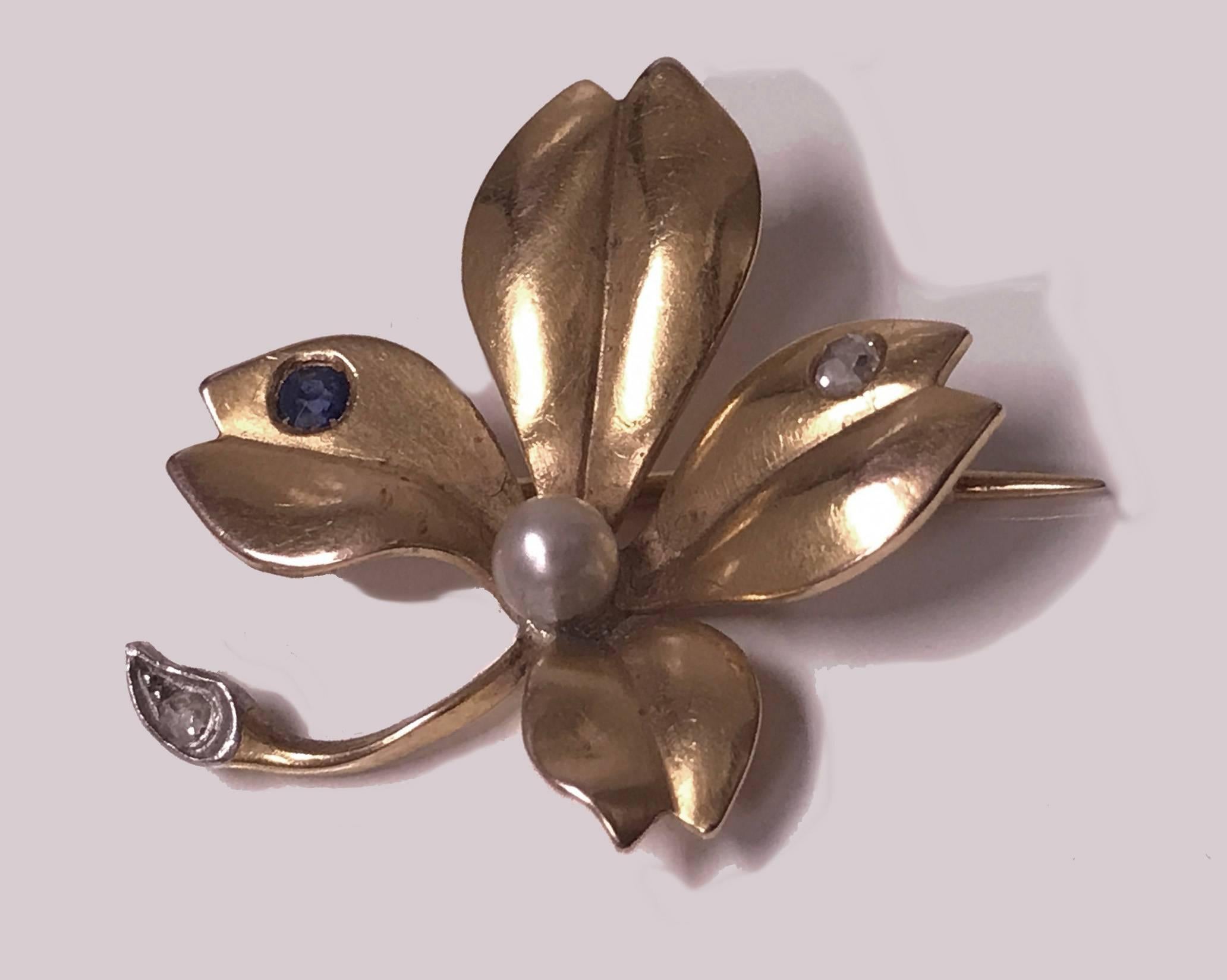 18K yellow gold, Sapphire, Diamond and Pearl Brooch in the form of a flower. France c.1900. The brooch of a four petal design, matte gold finish set with two small rose cut diamonds and a Blue Sapphire, centering a good quality cultured pearl,