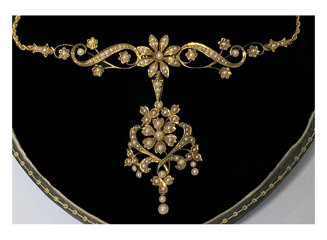 Antique 15ct Pearl Lavalier Necklace Pendant, English C.1890. The Lavalier with detachable pendant and brooch, of open floral scroll foliate design, set with approximately one hundred and two seed pearls. Clasp, Necklace and pendant drop all stamped