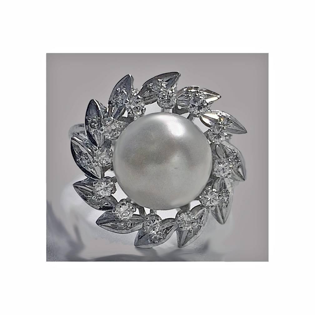 18K Pearl and Diamond cluster Ring. The top set with a fine round cultured pearl, gauging approximately 10.00 mm, silver white with pink overtone; the surround mount set with mixed small round cut diamonds, approximately 0.50 ct. total diamond
