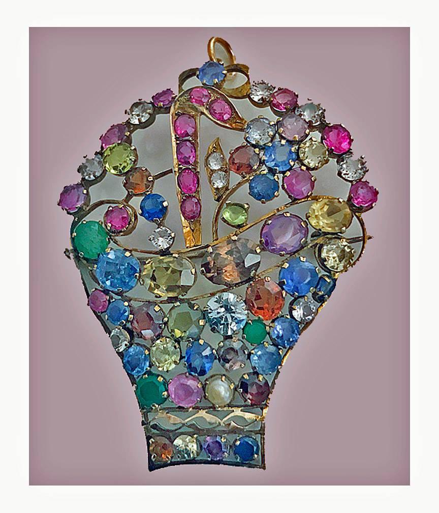 English Arts and Crafts Jardiniere Gemstone and Gold Brooch Pendant, C.1930. The basket of gemstones set with numerous pink, blue and white sapphires, peridot, emerald, zircon and quartz all set in 15K (tested) open floral design. Bar pin and safety