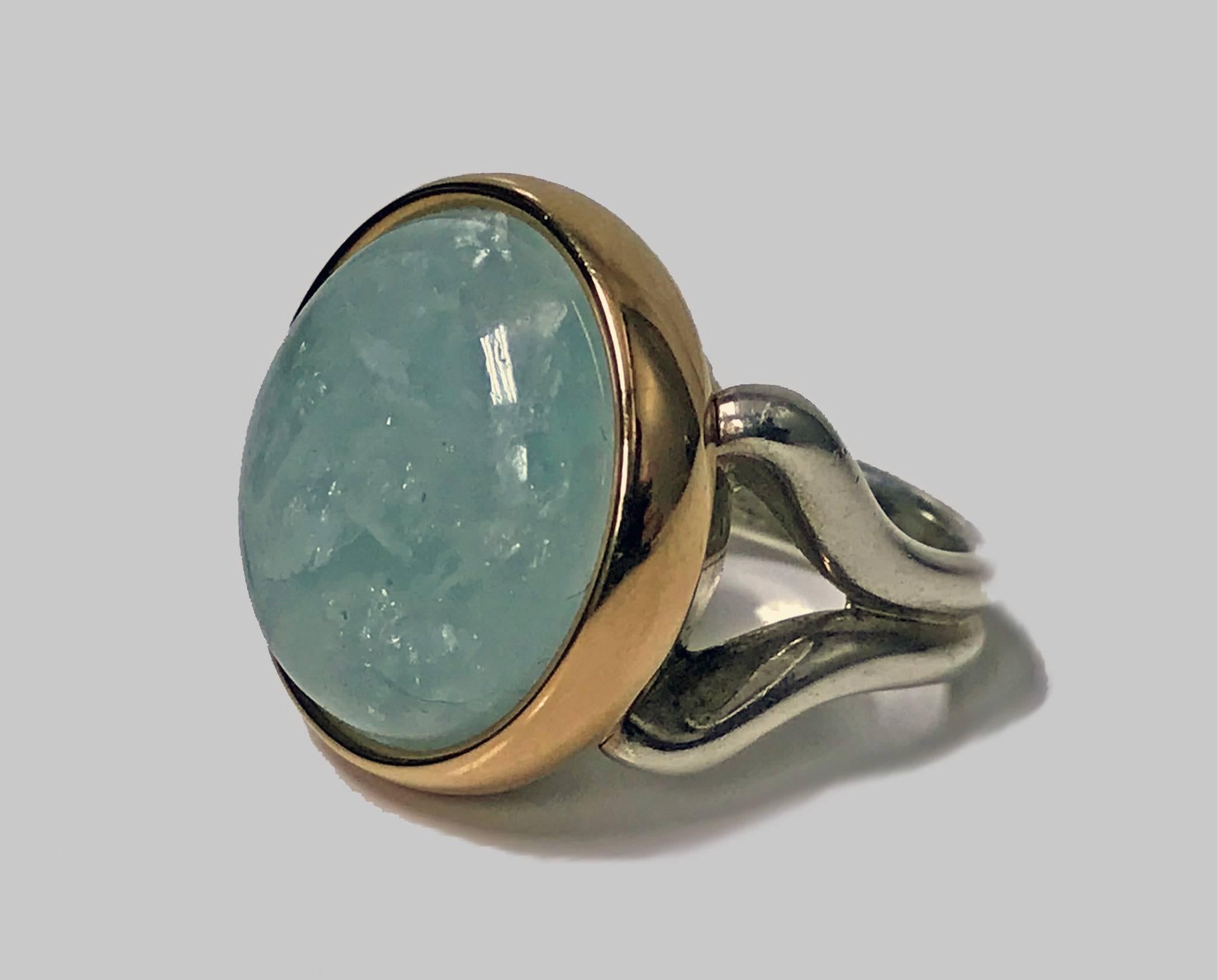 18K and Silver cabochon Aquamarine Ring. The custom designed ring 18K bezel set with a yellow green cabochon aquamarine, approximately 30 carats, included, the silver shoulders and shank of simple splay form. Total Item Weight: 23.1 gm. Ring size: 7