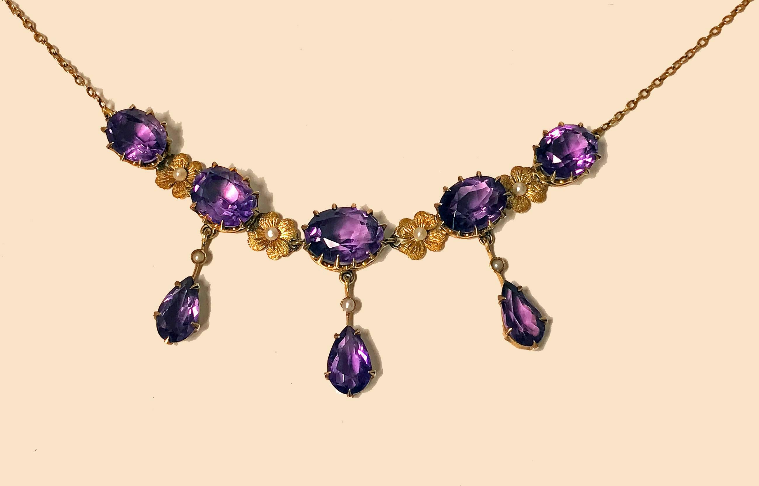 Early 20th century 14K Amethyst and Pearl Lavalier Necklace, American, C.1910. The Necklace claw set with five oval faceted medium tone amethyst, inter spaced with gold floral seed pearl rosettes, three amethyst suspending tear drop amethyst