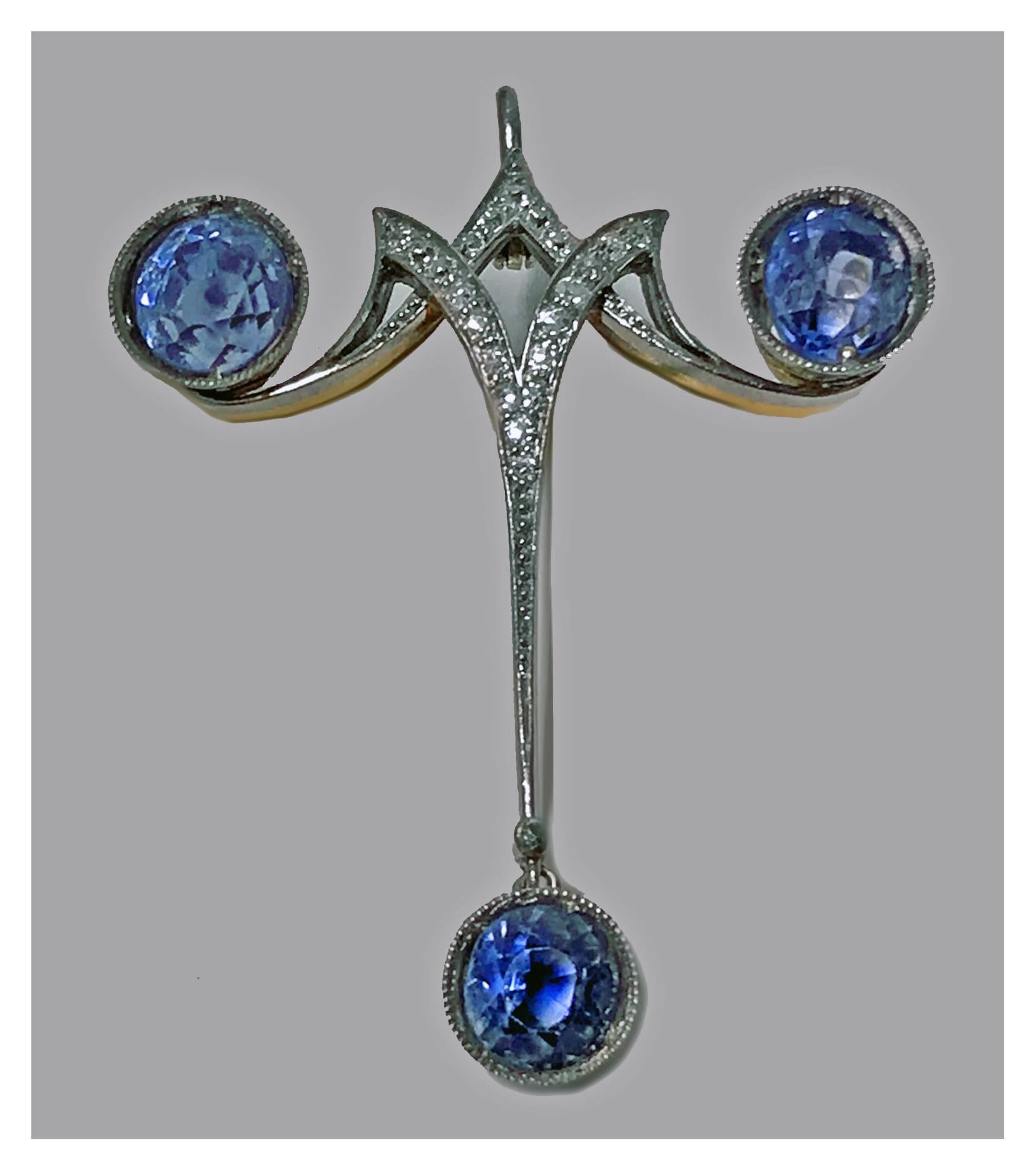 Edwardian Platinum and 18K Sapphire and Diamond Pendant Brooch, C.1910. The pendant brooch of a `comet’ off twist style shape milligrain set with three round faceted medium violetish Blue Sapphires, approximately 3.80 cts, total sapphire weight, SI