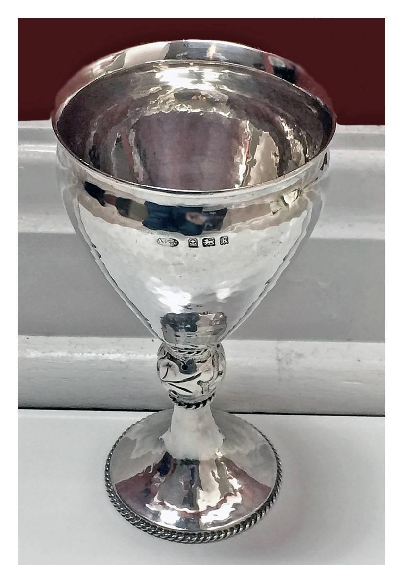 A.E. Jones hammered Sterling Silver Goblet, Birmingham 1909. The goblet of plane hammered decoration on pedestal foot, with rope border surround rising to foliate knopped stem and vase shape vessel, everted rim. Full silver hallmarks and retailers