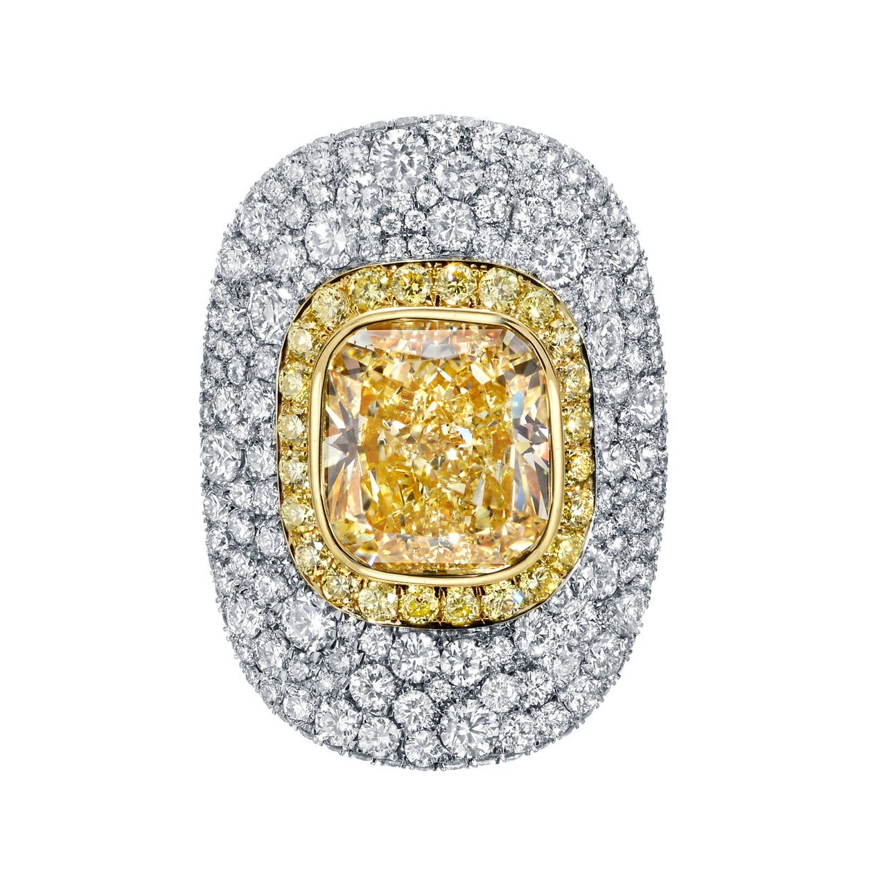 A magnificent 5.30ct, VS2, cushion, light yellow diamond, is surrounded by fancy yellow diamonds totaling 0.51ct, and 