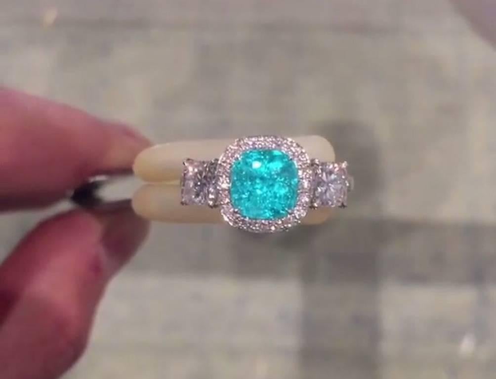 1.82 carat cushion cut Brazilian Paraiba Tourmaline ring, displaying an intense greenish-Blue color and a unique neon phenomena that is characteristic of the original Batalha mine in Paraiba Brazil. This gem is flanked by a pair of G color and VS1