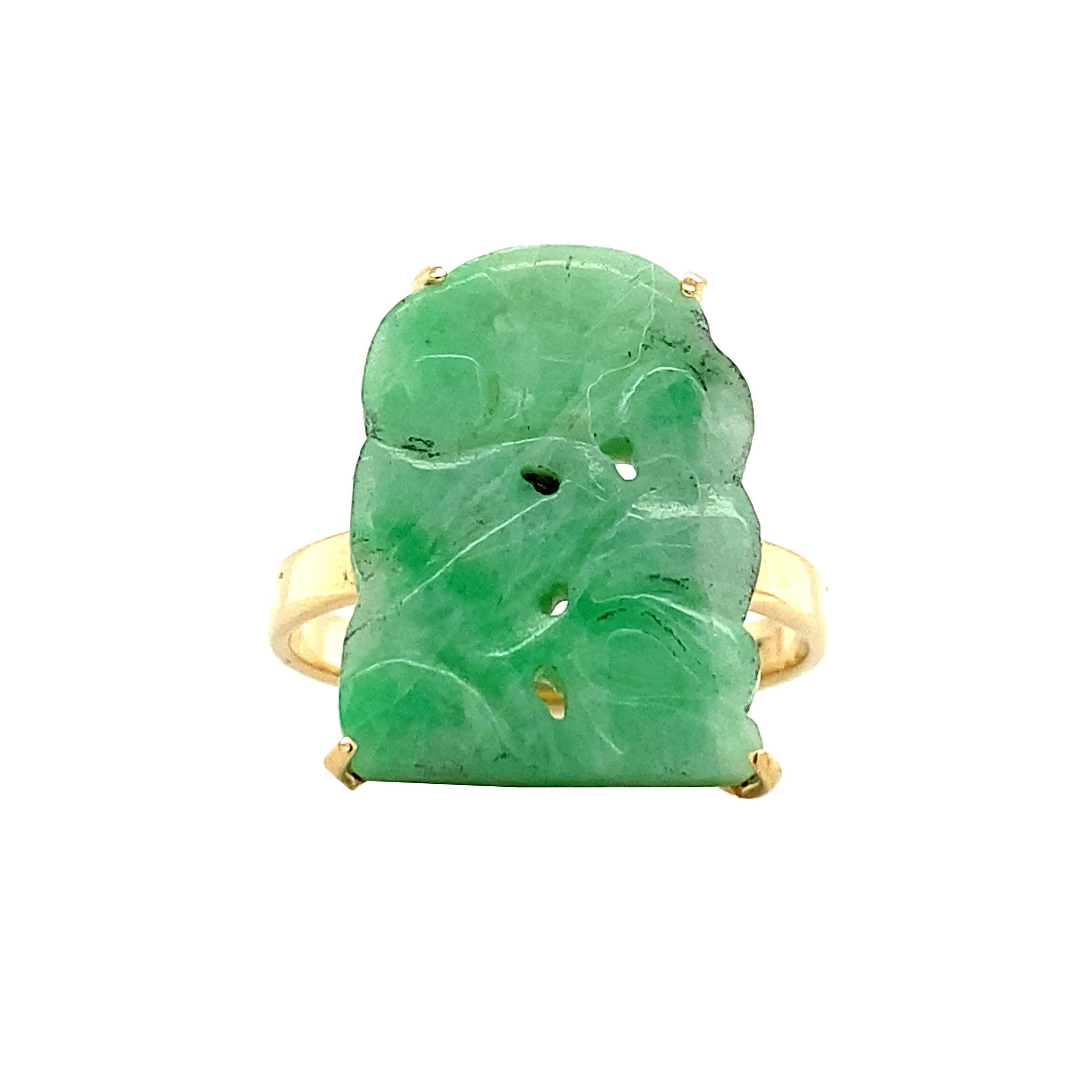 La giada verde è intagliata con motivi floreali  in una bellissima targa e incastonata in una montatura in oro giallo 14k, in cima a una fascia d'oro. Un singolare mix di eleganza e spazio negativo, questo anello è squisito. La giada è