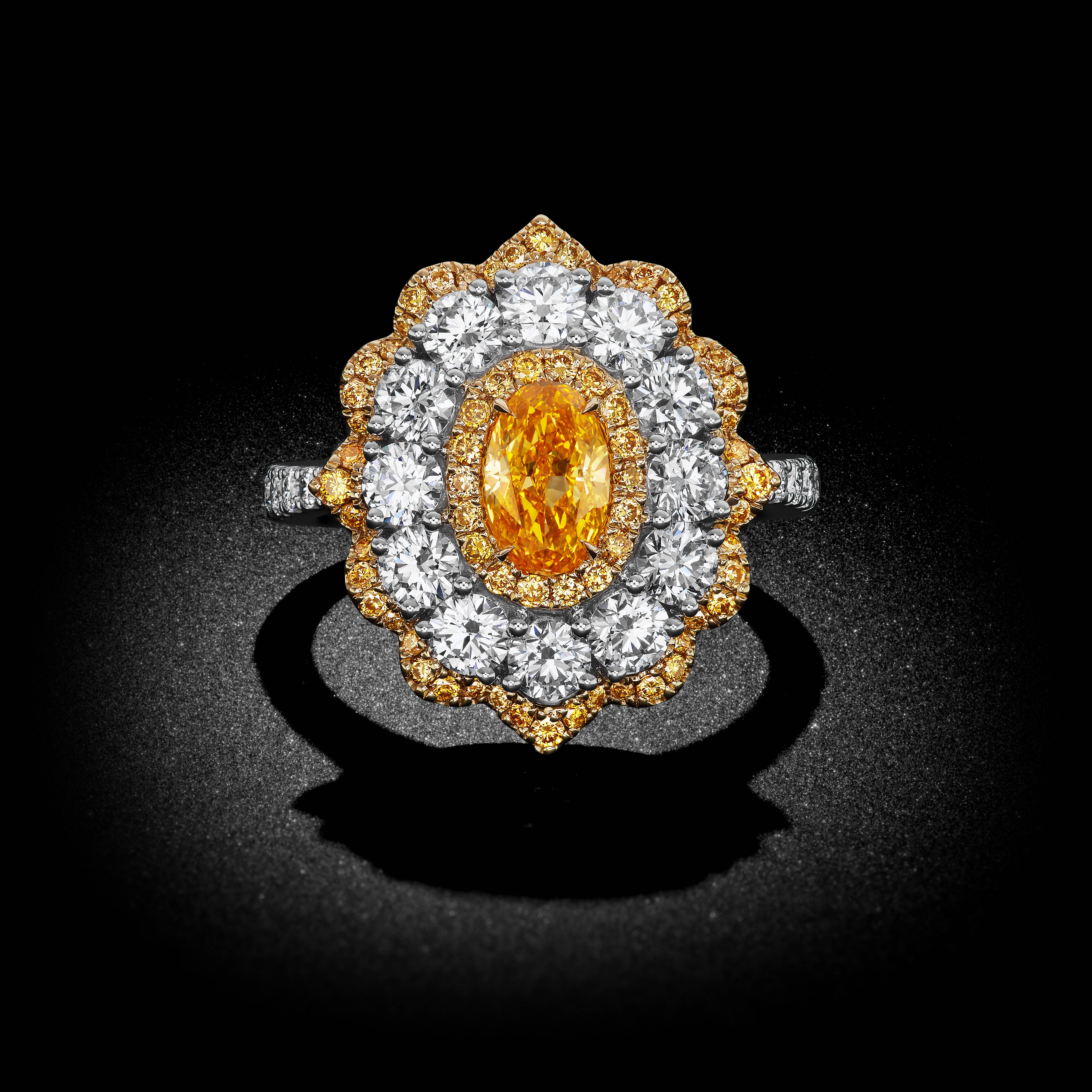 This astounding masterpiece gleams with a resounding display of color and brilliance. And incredibly rare Fancy Intense Yellow Orange oval diamond rests within a bright unfurling flower. Over 2 carats of white and yellow round brilliant diamonds