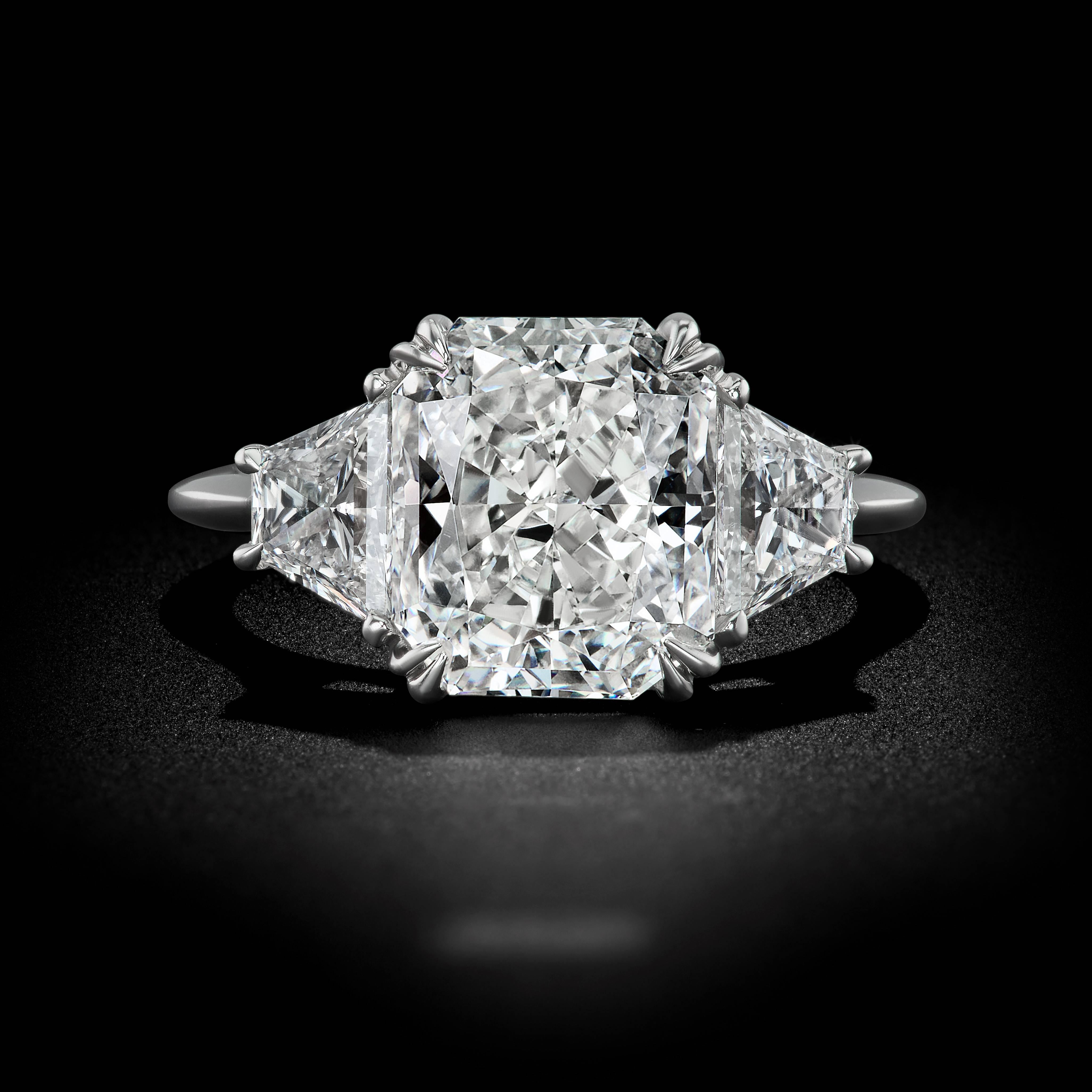 Eine großartige Interpretation eines traditionellen Designs. Dieser beeindruckende Verlobungsring mit drei Steinen vereint eine feurige Kollektion leuchtender Diamanten auf einem Band aus Platin. Ein lupenreiner 4::04-Karat-Diamant im