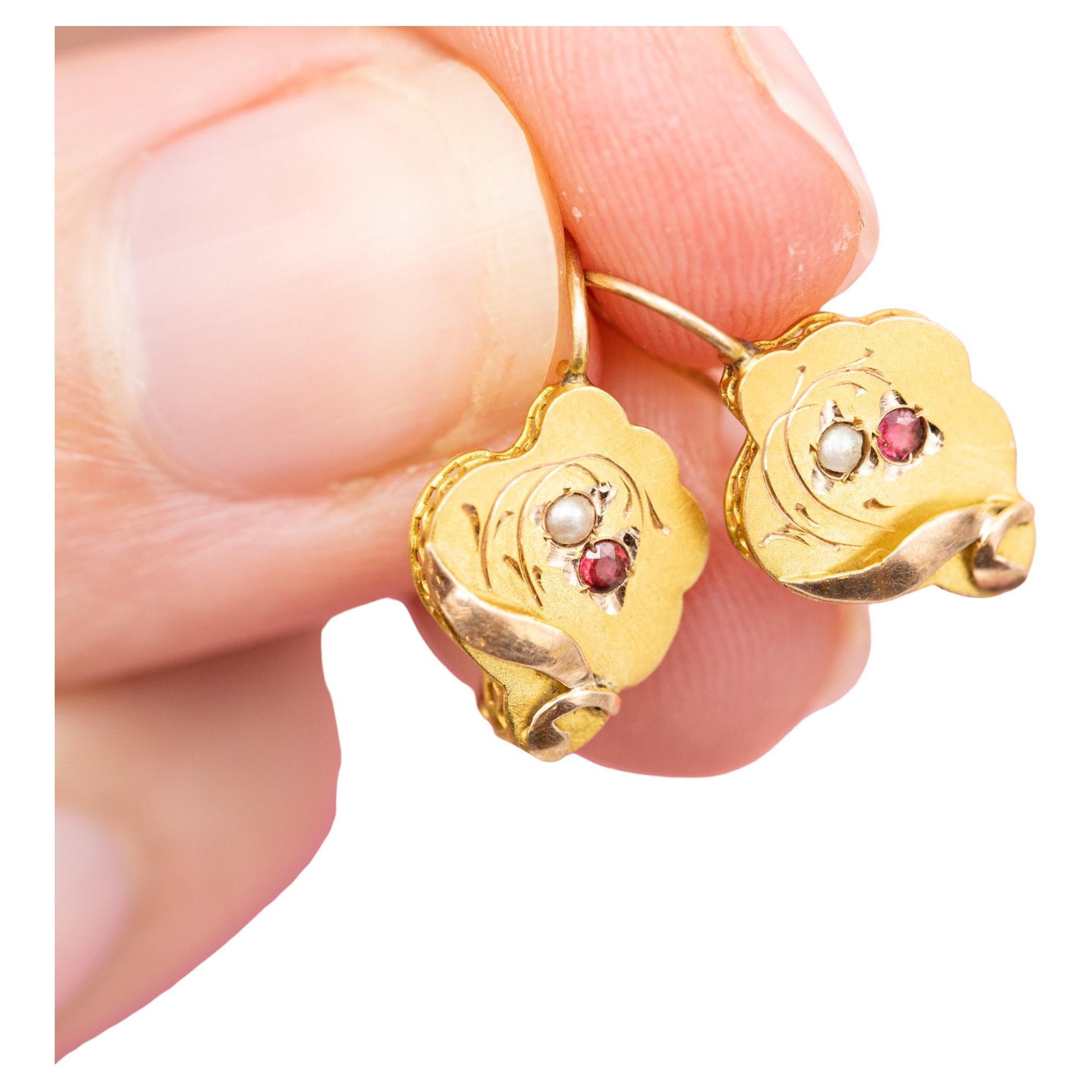 For sale are these romantic Victorian earrings. These 18 ct yellow gold dormeuse earrings (also called sleepers) are decorated with flower shaped ornaments, little seed pearls, rubies and are finished with a lot of detail. The fine details are well
