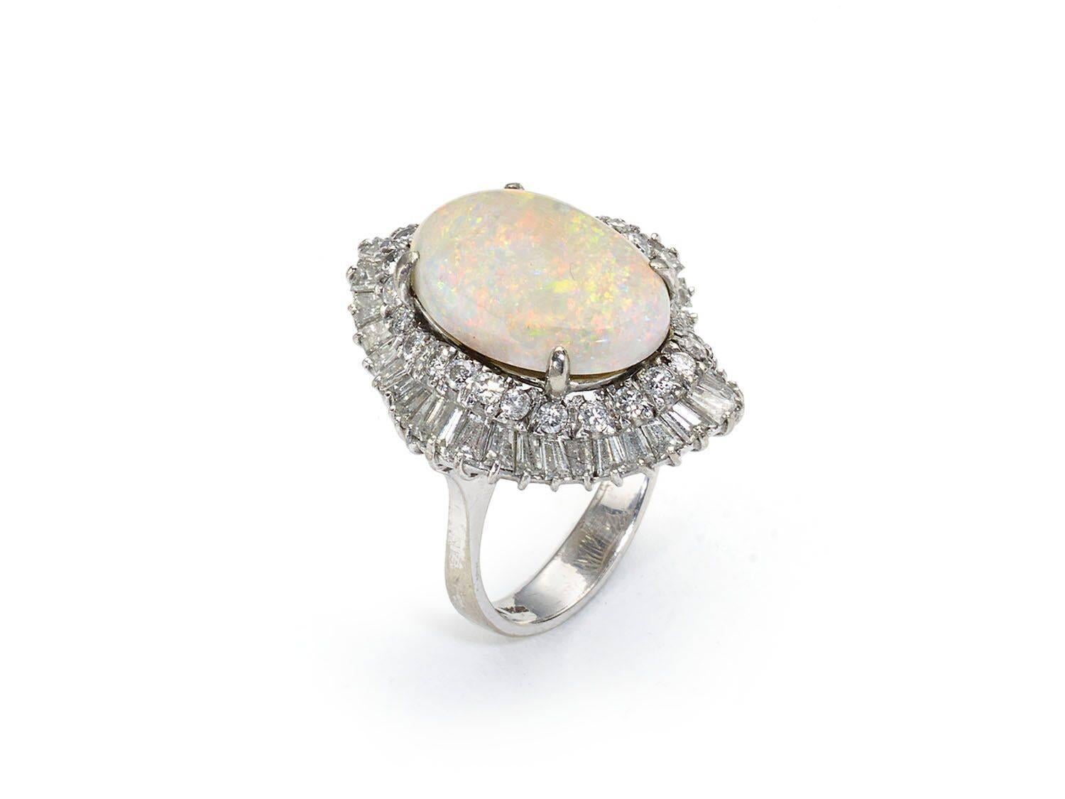 An opal and diamond ballerina ring, with tapered baguette and round brilliant-cut diamonds, surrounding an oval milky opal, mounted in 14ct white gold.
Estimated diamond weight 3.00cts Opal measuring 18mm x 13mm x 6.5mm 