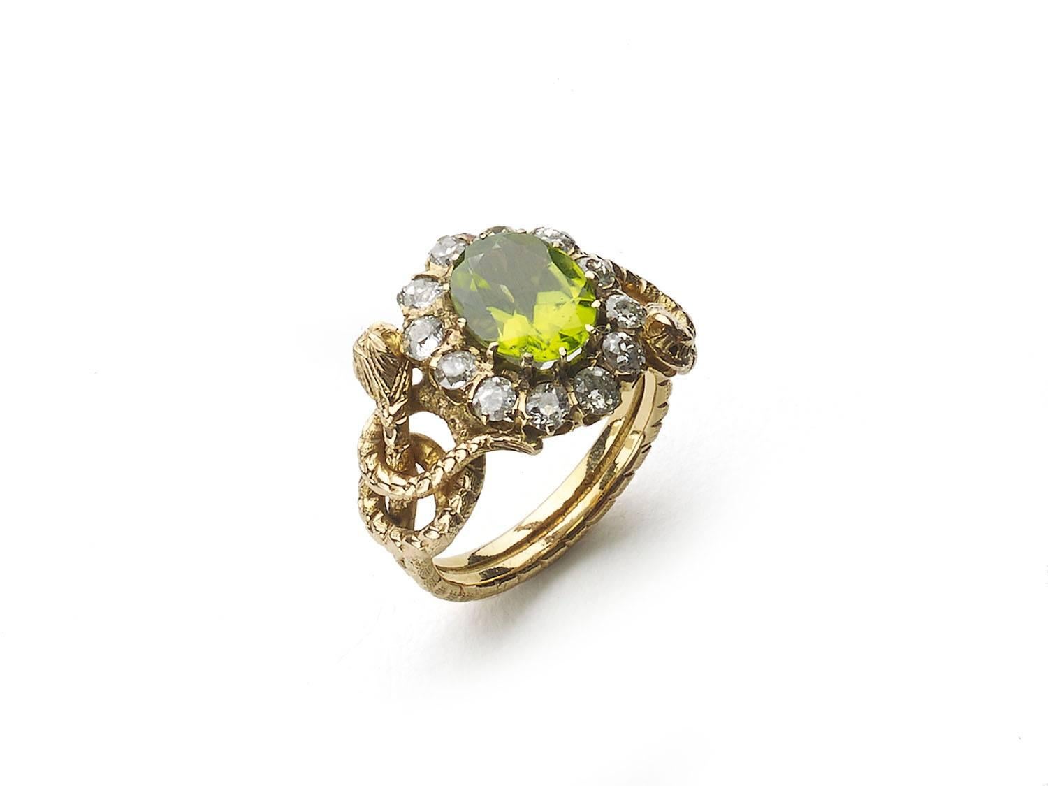 A Victorian peridot and diamond ring, central oval cut peridot weighing an estimated 1.20ct, surrounded by twelve old cut diamonds weighing an estimated total of 1.00ct, with a coiled snake to each shoulder, mounted in yellow gold, circa 1880, ring
