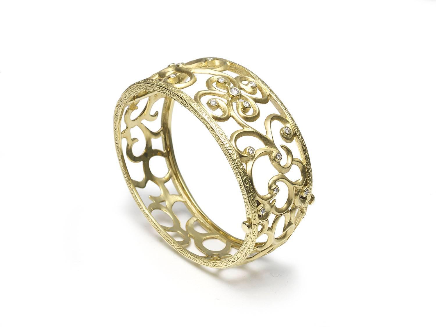 An 18ct gold hinged bangle, wide tapering bangle, with an openwork design set with rub-over set round brilliant cut diamonds weighing an estimated total of 0.40ct, outer edges with engraved detail, inside diameter measures 55 x 47mm