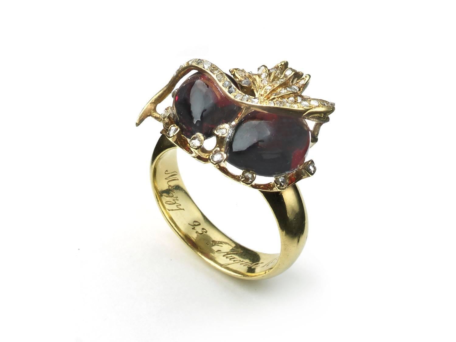 An antique snake and double garnet ring, set with two, cabochon-cut, pear shape garnets, with surrounding claws set with rose-cut diamonds, with a superimposed gold snake, set with rose-cut diamonds, with a rose-cut diamond set gold flame at the