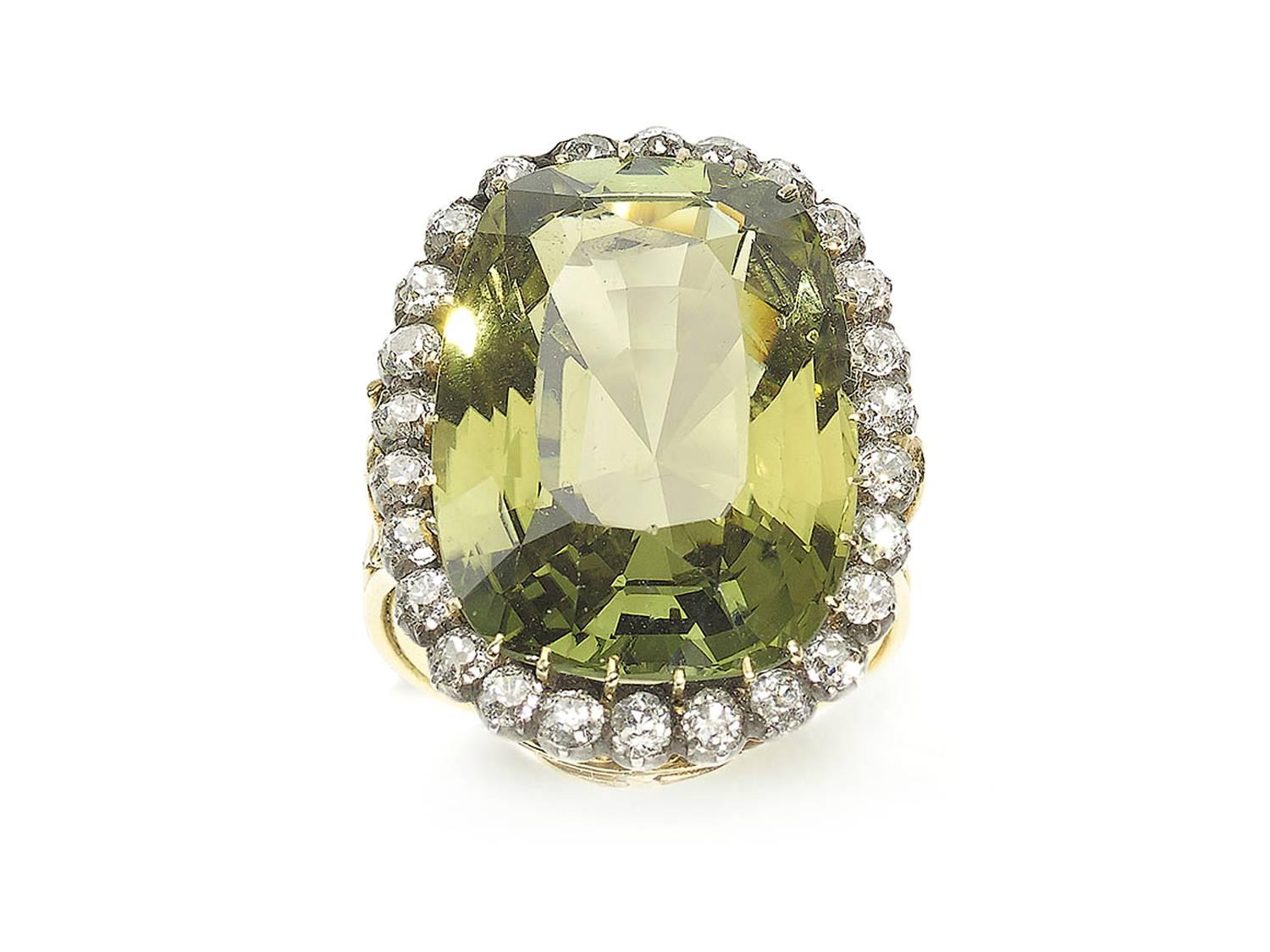A chrysoberyl and diamond ring, central oval chrysoberyl weighing an estimated 25.45ct, surrounded by old cut diamonds weighing an estimated total of 1.30ct, mounted in yellow gold. Finger Size UK K / US 5⅛