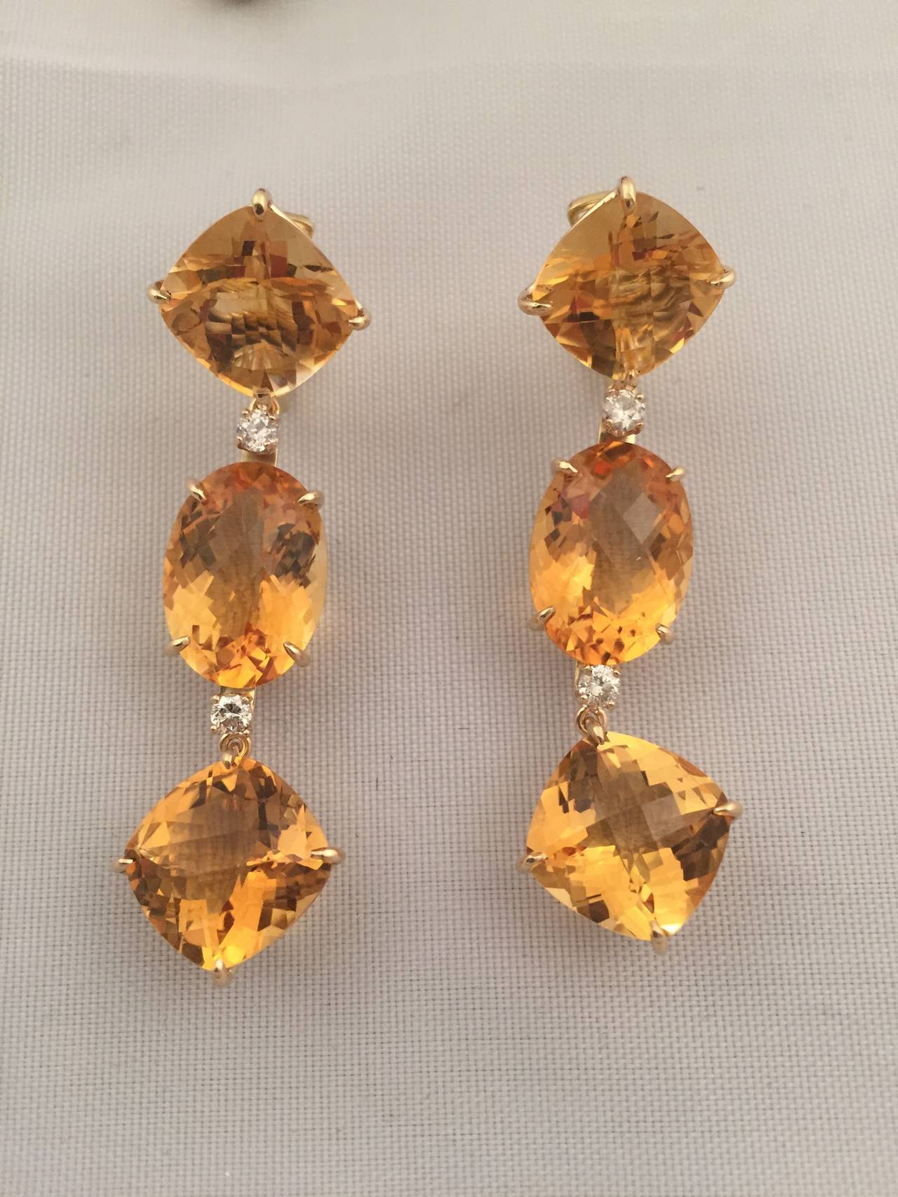 Elegant Citrine and Diamond Three Stone Drop Earrings.  18kt Yellow gold with faceted Cushion, Oval and then Cushion cut Citrine finished with four diamonds ~0.60cts.  The earrings measure  2 1/2" in length and  1/2" wide.

The earrings