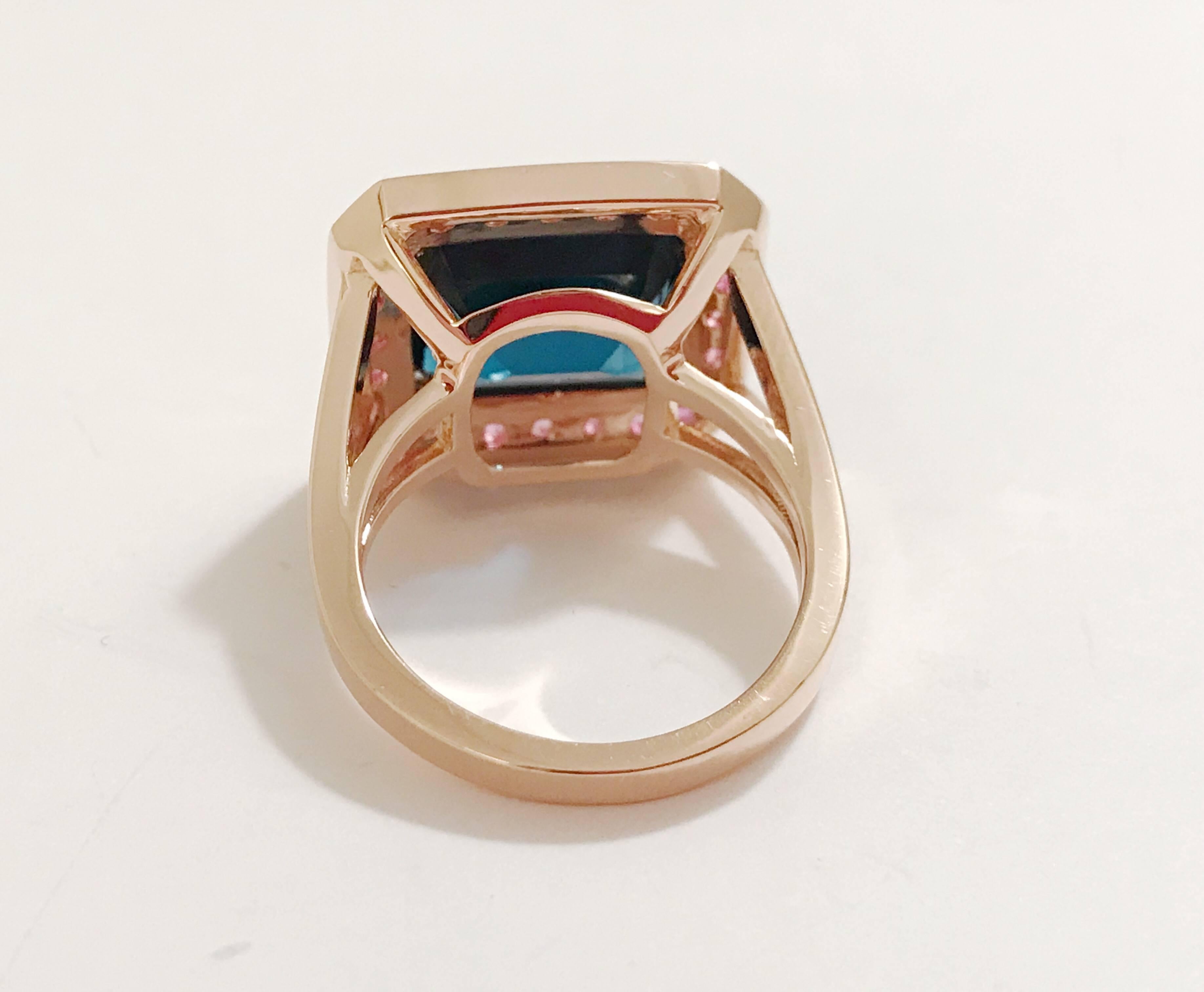 18kt Rose Gold and Split Shank Ring with Emerald Cut Dark Blue Topaz Center Stone with surrounding Pink Sapphires is an elegant cocktail ring. Measures 0.75 across the top.

This Ring can be made with any color center stone as well as type of