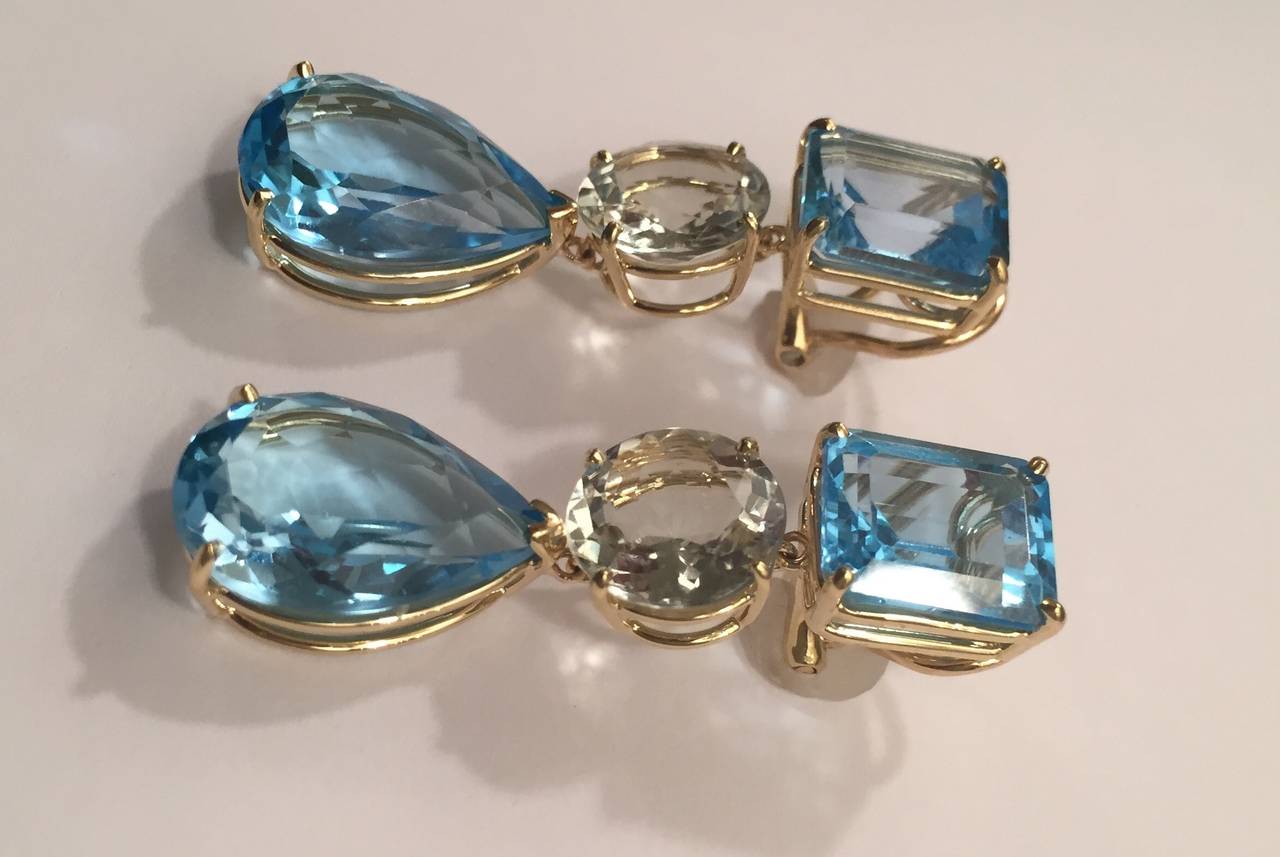 18kt Yellow Gold Geometric three stone drop Earring with Emerald Cut Blue Topaz, Round Green Amethyst and Pear shaped Blue Topaz Drop.

The Earring measures 1 and 3/4