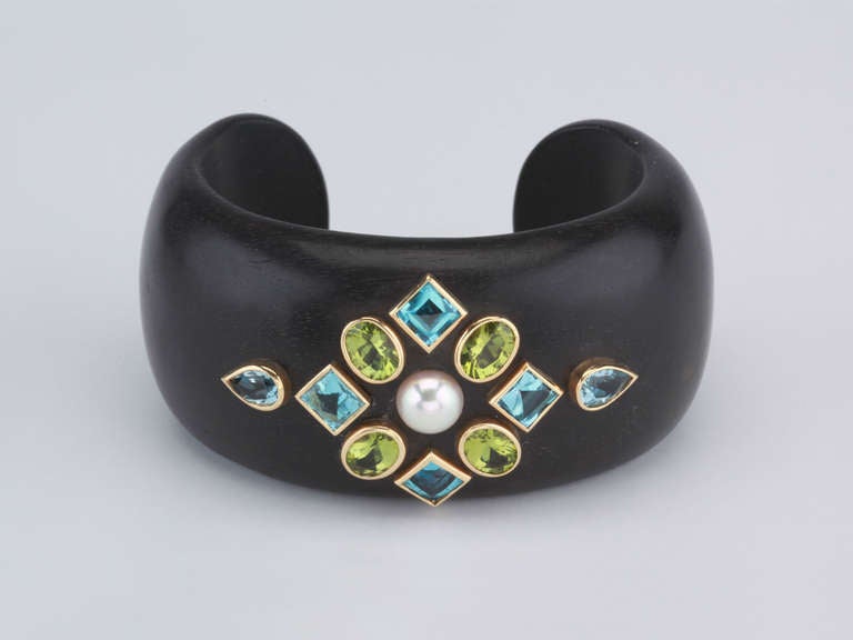 Wood cuff bracelet with peridot, blue topaz, and pearl set in 18kt yellow gold. 

Measures a 5