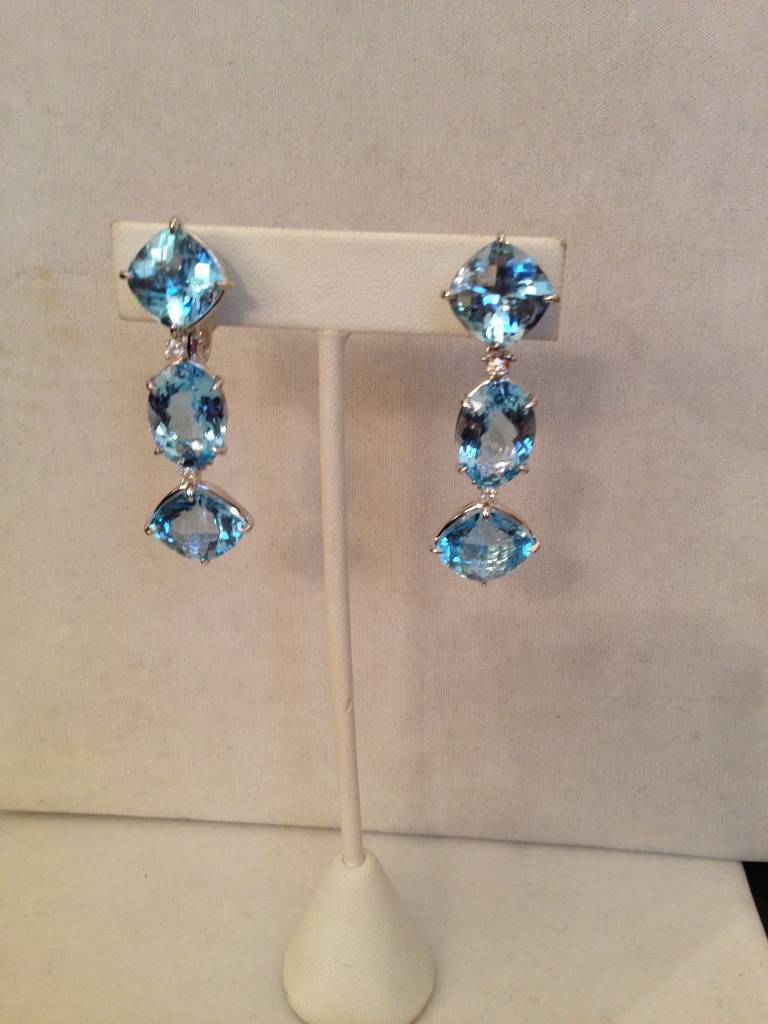 18kt White Gold Blue Topaz and Diamond Three Stone Drop Earring with Cushion and Oval Blue Topaz and 4 diamonds.  Can be pierced or Clip  Length is approximately  2 1/4 inches long and 1/2' wide.