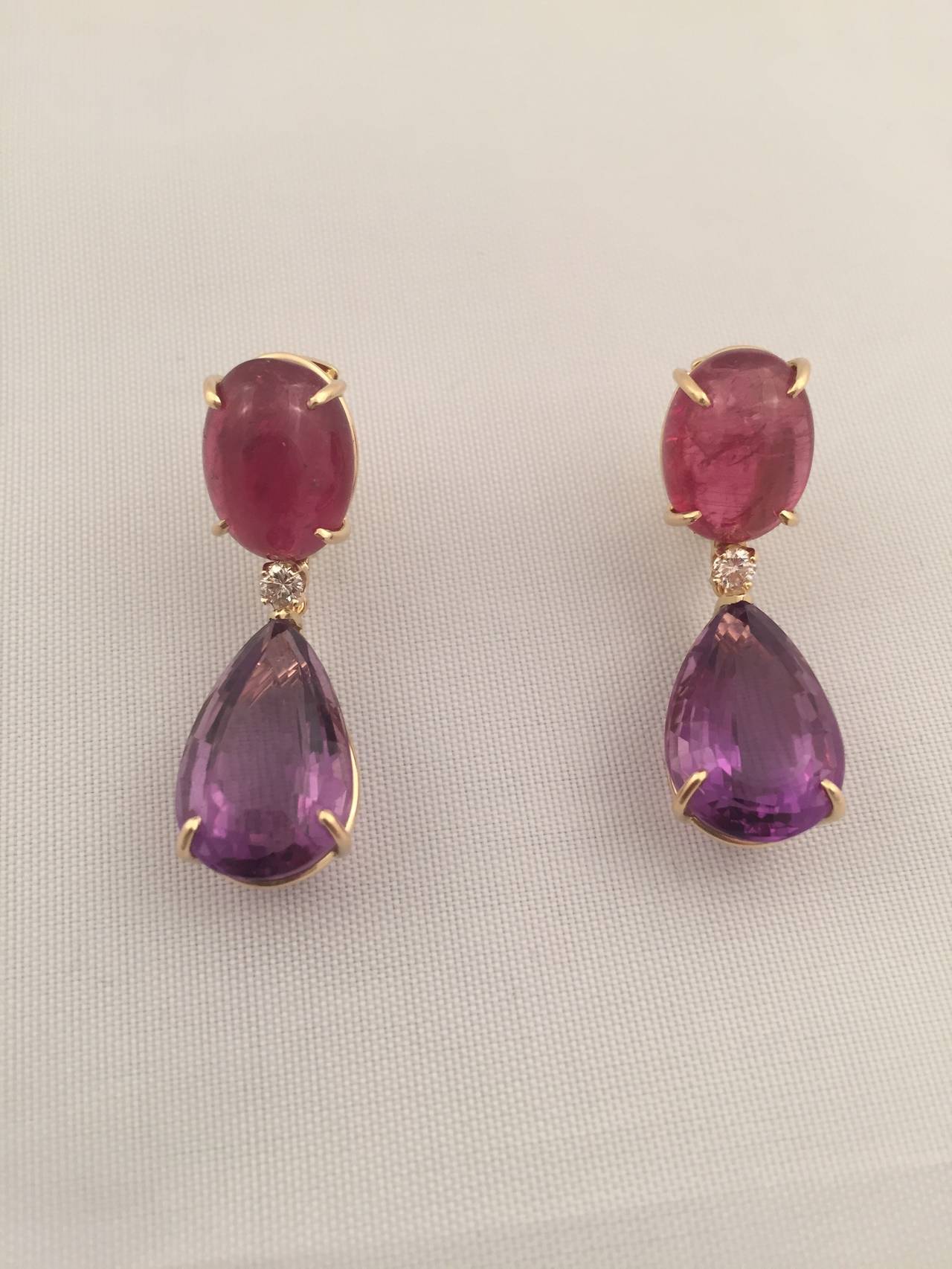 18kt Yellow Gold Drop earring with Oval Cabochon Rubelite and faceted pear shaped drop Amethyst Drop with center Diamond detail ~.30cts.
Rich color combination and Elegant Drop to complement any Face shape!

The earring measures ~ 1 1/2