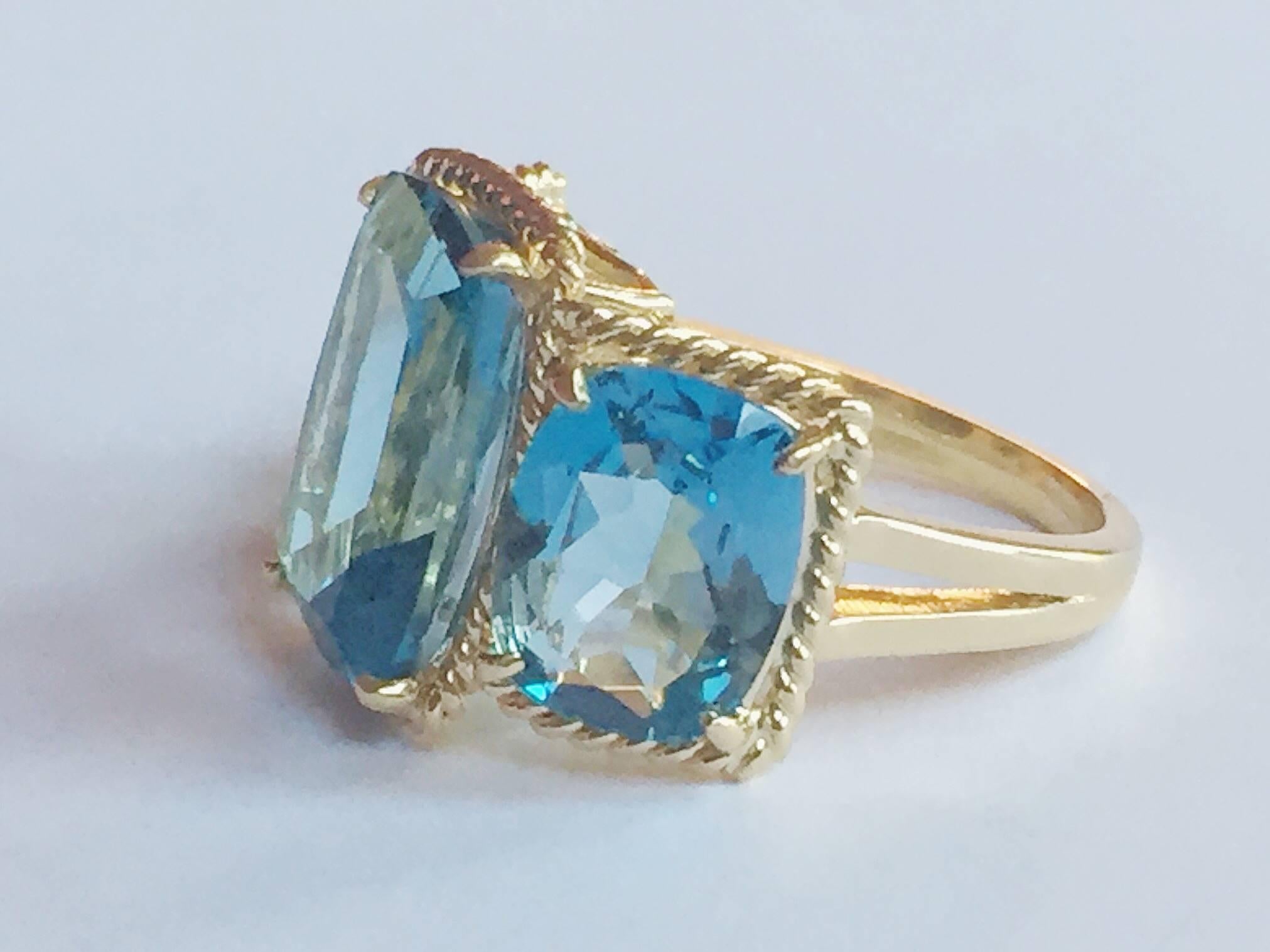 Elegant 18kt Yellow Three Stone Ring with Rope Twist Border with split shank detail. The ring features three faceted Blue Topaz cushion cut stones surrounded by twisted gold rope. The center Blue Topaz stone measures 5/8