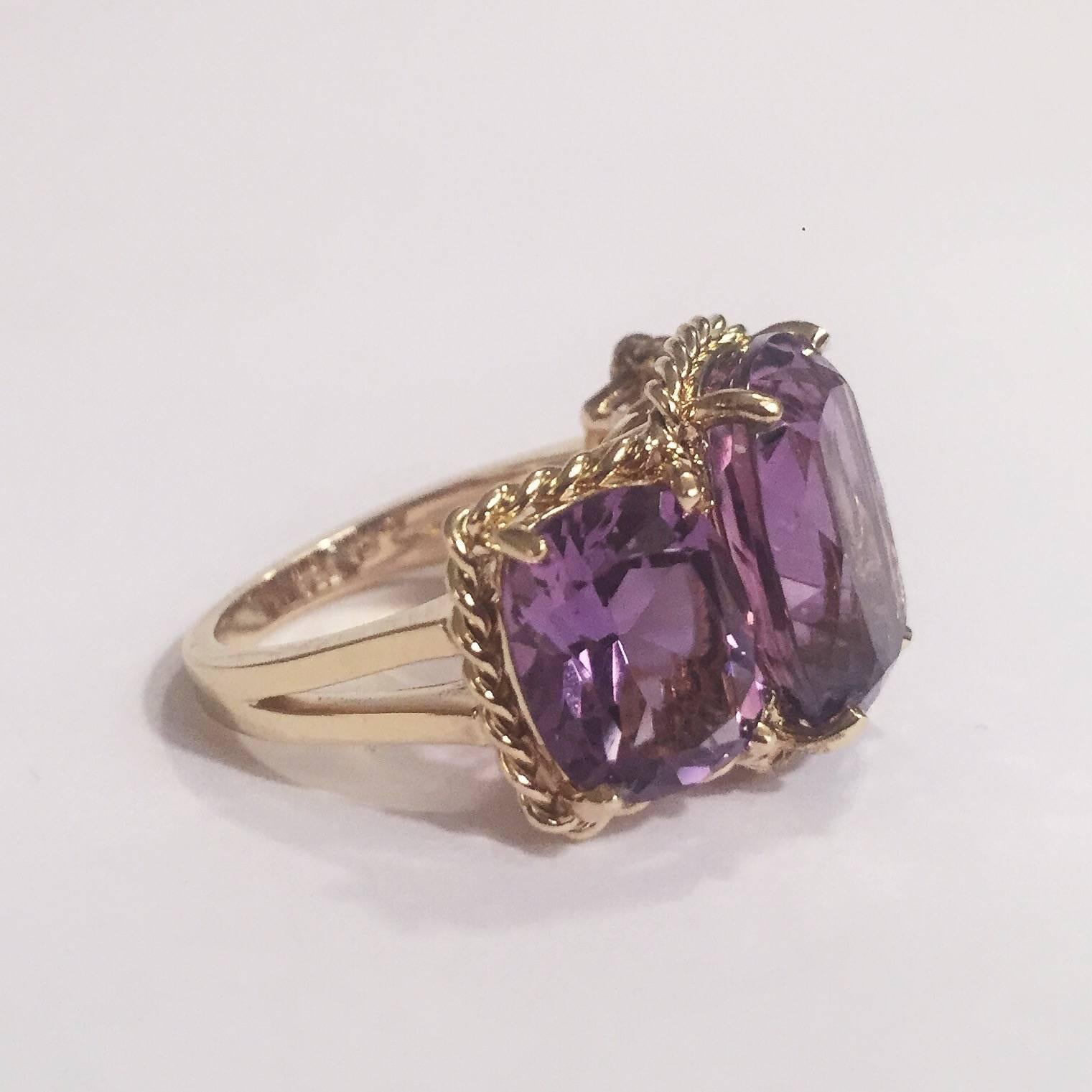 Elegant 18kt Yellow Three Stone Amethyst Ring with Rope Twist Border with split shank detail. 

The ring features faceted cushion cut Amethyst stones surrounded by twisted gold rope. The center Amethyst measures 5/8