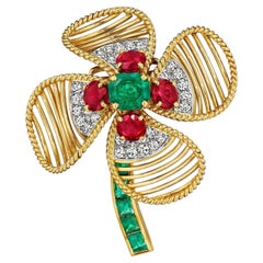 Broche de Cartier París, de mediados de siglo, con esmeraldas, rubíes, diamantes y una flor de oro