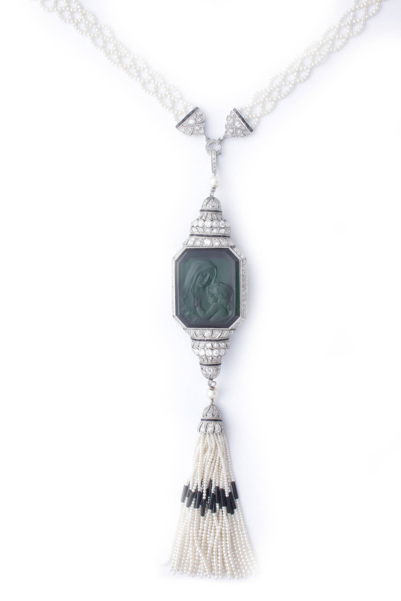 An exquisite and rare Art Deco sautoir composed of an intrigued natural pearl triple strand suspending a detachable central element, presenting a fine quality large carved green Tourmaline representing the 