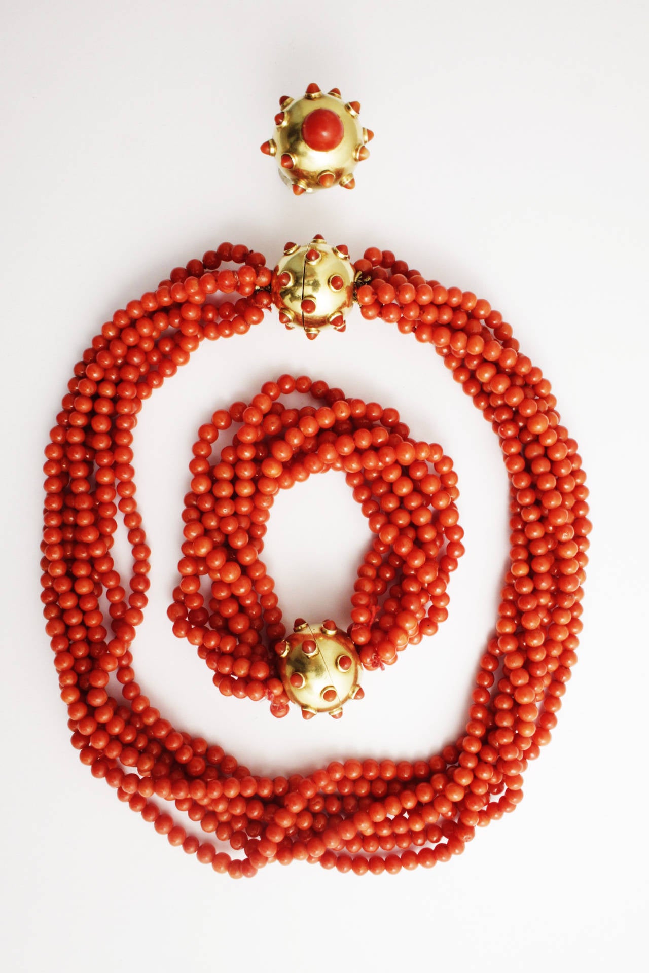 A peculiar parure manufactured by Giorgio Bulgari in during the 1940s. The necklace and bracelet consisting of 7 twisted strands of fine red coral, interconnected and clasped by an 18kt gold sphere, originally embellished by coral spikes. The ring