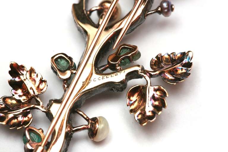 A sophisticated brooch manufactured by Buccellati (Milan) in the 1970s, representing a tree branch in 18kt white gold, decorated with carved emerald leaves, 18kt gold leaves and pearls.