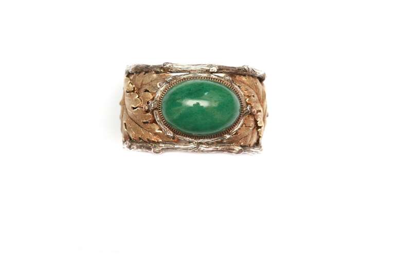 A cuff bracelet, to be opened from one side, manufactured by Buccellati (Milan) during the 1970s, presenting a large oval-shaped aventurine, set in mixed 18kt white and yellow gold, embellished with the glazed leaf and branches motifs typical of the