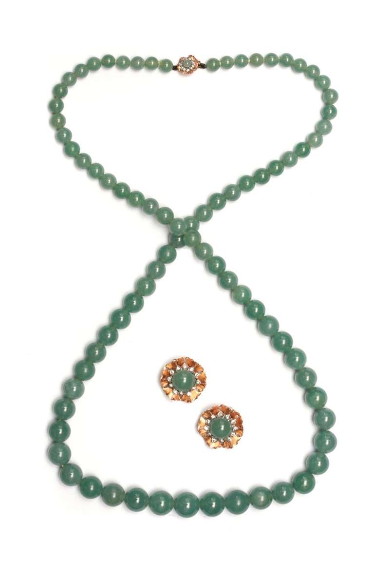 A demi-parure comprising necklace and earrings presenting 82 beads of jade of diameters ranging between 1.2 and 0.6 cm. The necklace's clasp and earrings are mounted on 18kt gold and embellished with floral motifs and small brilliant cut diamonds.