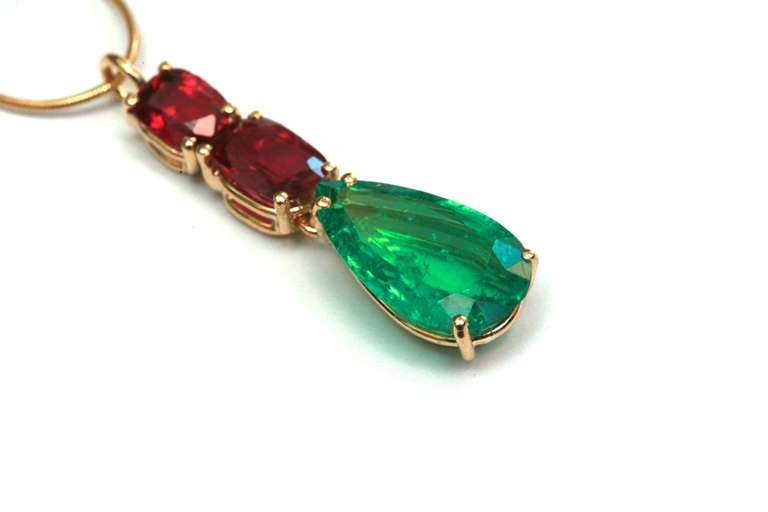 A pendant necklace composed of a 4.2 carat Colombian emerald of fine quality colour and brilliance (most probably of old mine material), sided by two smaller tourmalines, on an 18kt yellow gold mounting.