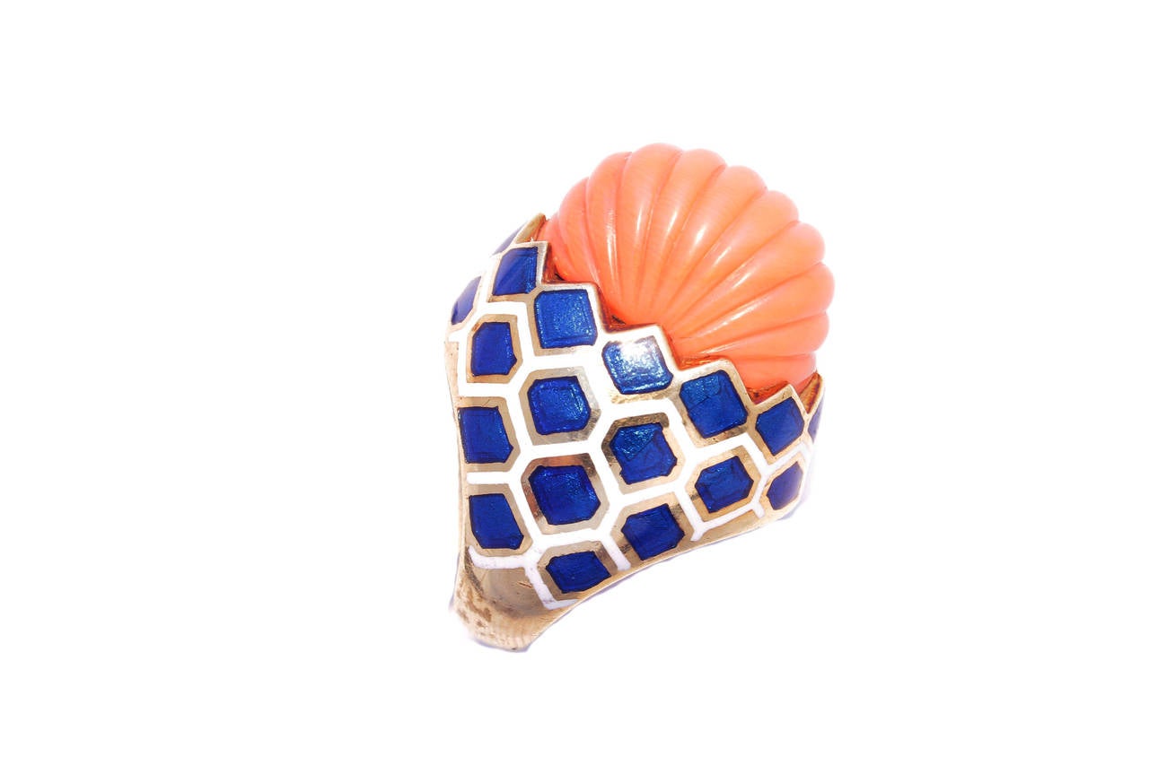 A colourful cocktail ring presenting fine white and blue enamelling, sustaining an element of domed shape red coral, on an 18kt yellow gold mounting. United States, circa 1970.