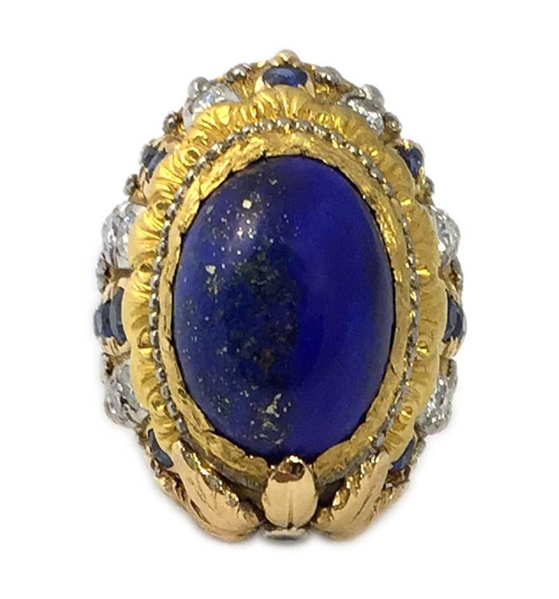 A chunky cocktail ring by esteemed Roman jeweler Cazzaniga, centering a dome shaped lapis element, showcased in an 18kt yellow gold mounting with floral motifs, highlighted with brilliant cut diamonds and sapphires. Italy, circa 1965.