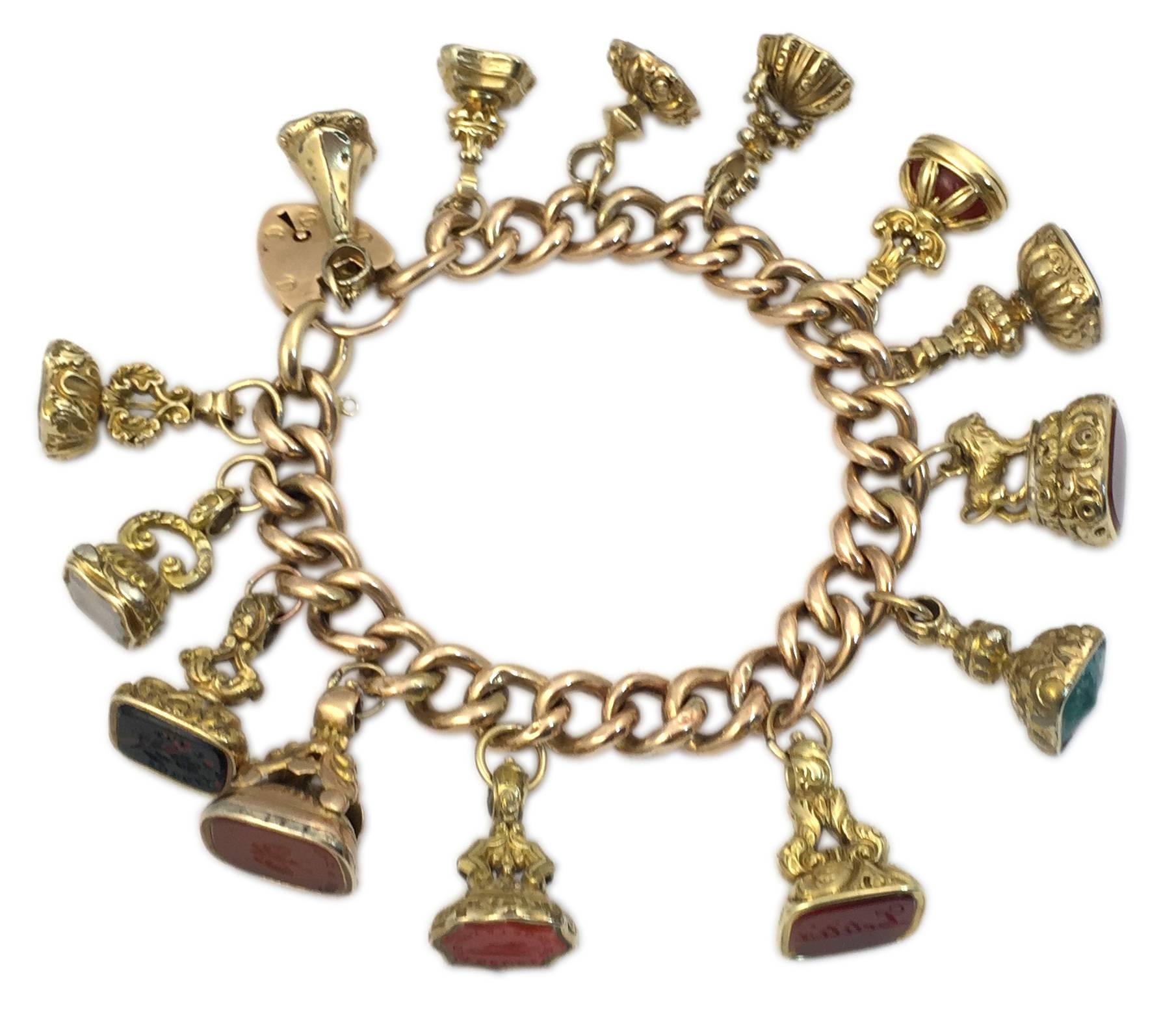 Un singulier bracelet à breloques composé d'une chaîne à maillons de 18 carats, suspendant quatorze sceaux en pierre dure. Circa 1960 