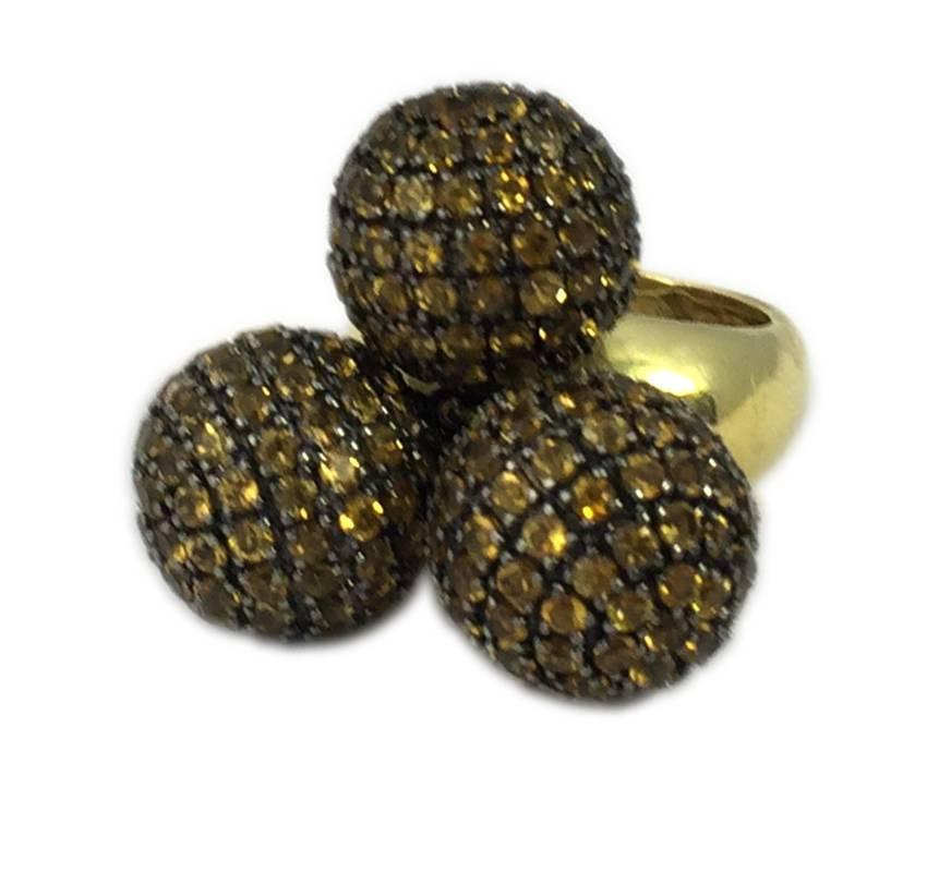 Une bague amusante composée de trois sphères en argent incrustées de citrine et suspendues à un anneau en or jaune 18 carats. Les trois sphères bougent si l'anneau est incliné. Italie, vers 1980 
