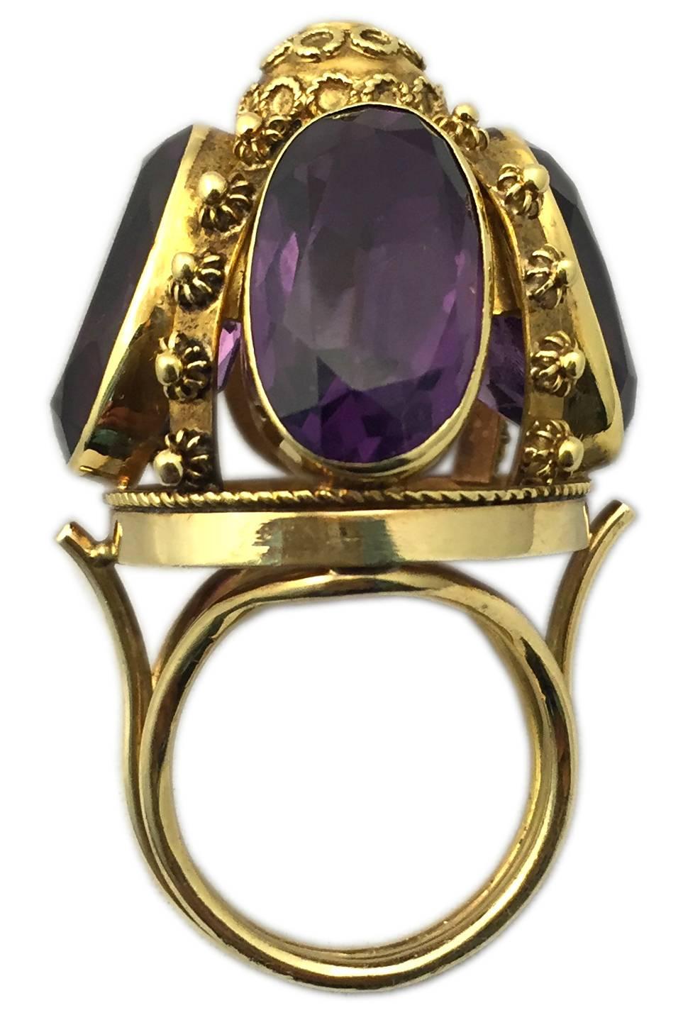 An antique dome shaped 18kt yellow gold ring, showcasing four oval cut amethysts on its side, embellished by a brilliant cut diamond on its top, presenting fine filigree gold decorations. Circa 1880