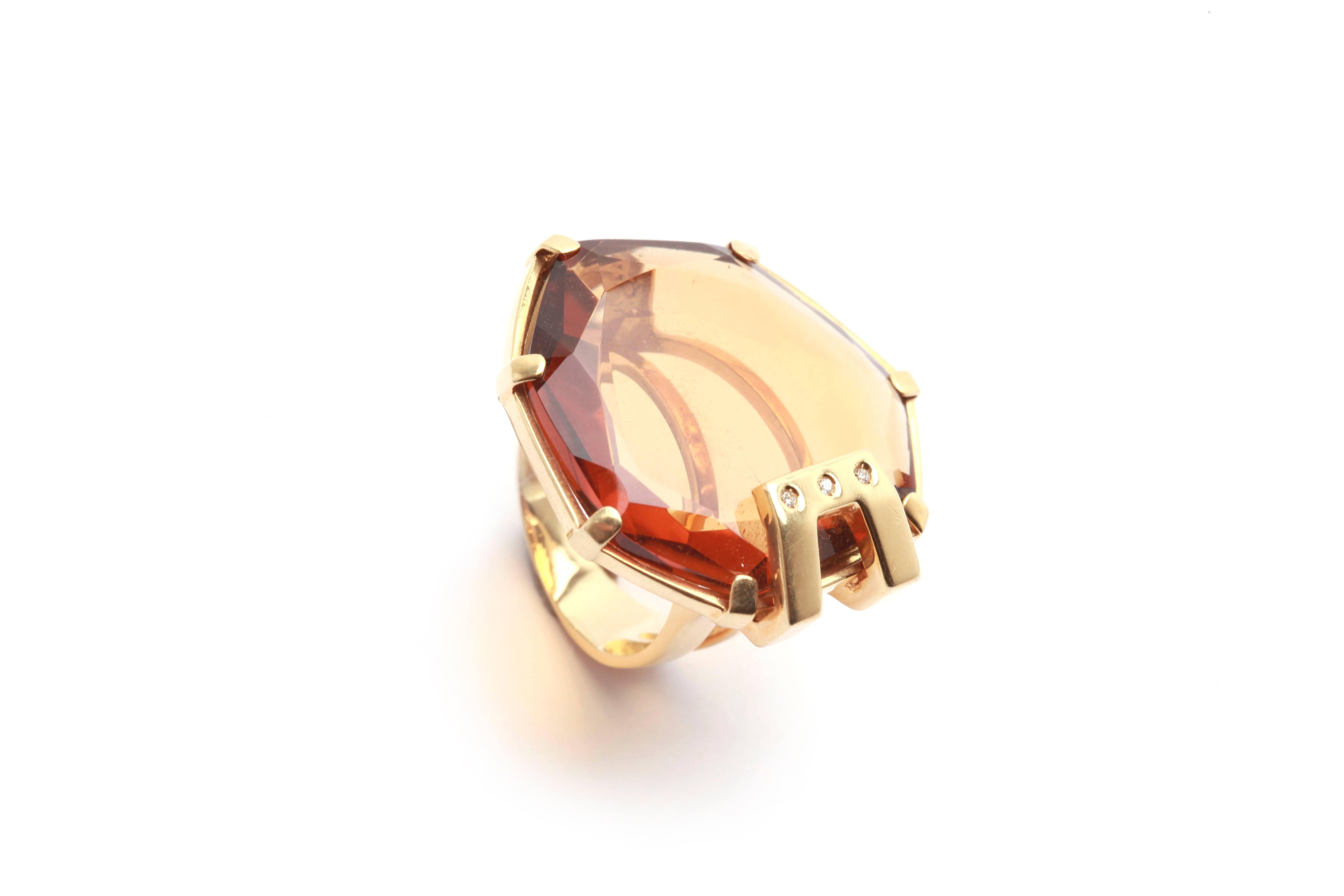 A fun flatly cut citrine cocktail ring mounted on fine buckle shaped 18kt yellow gold, highlighted with three small diamonds. Circa 1970