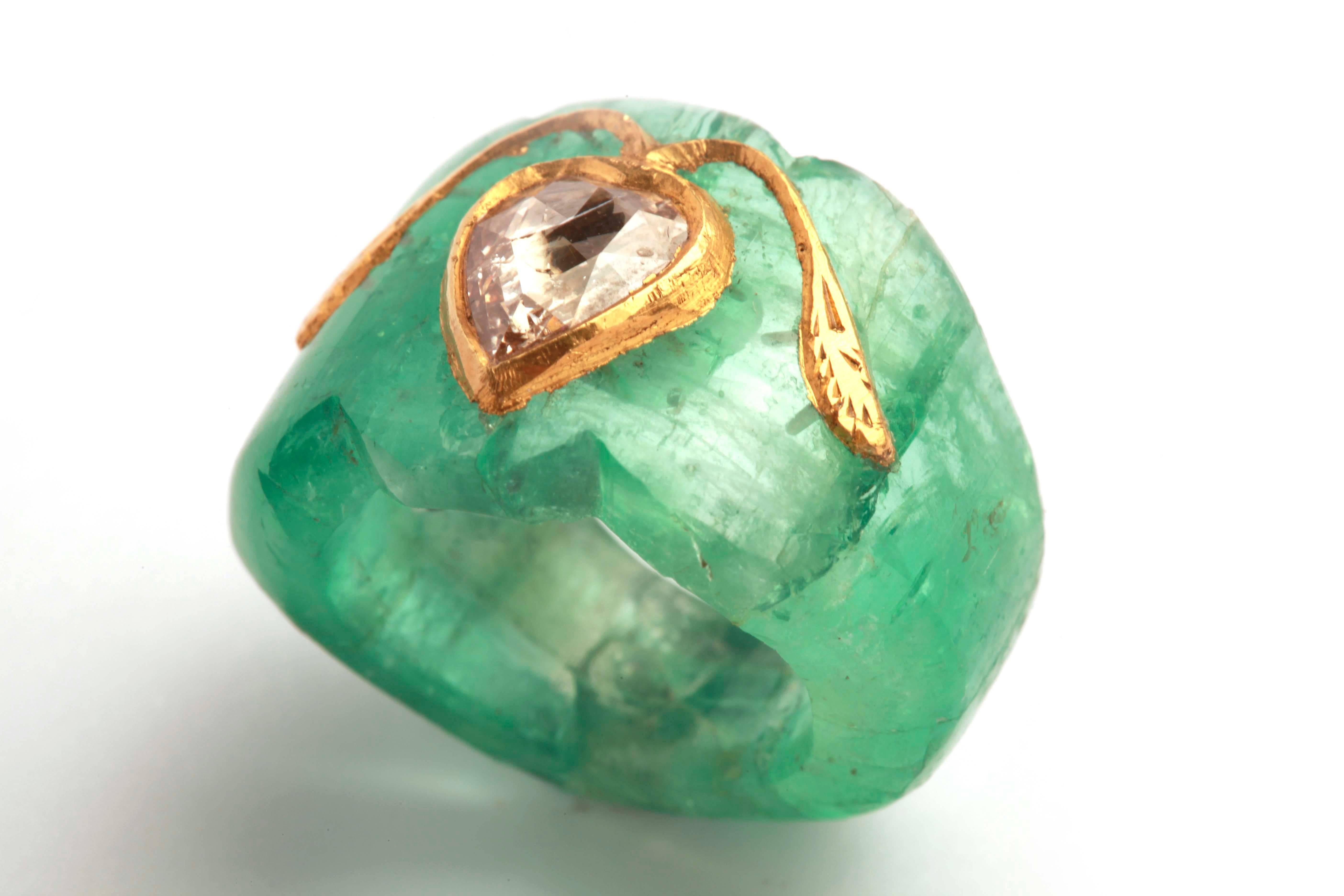 A peculiar ring carved out of a 50ct Colombian emerald, highlighted with a rose cut diamond on a yellow gold motif. Circa 1950